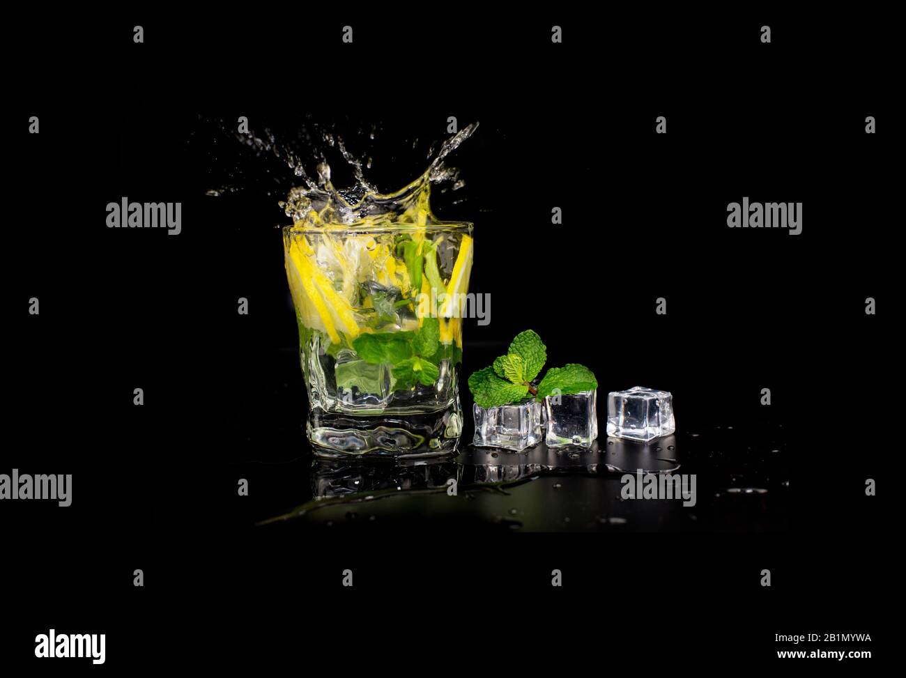 mojito cocktail drink with mint and lemon lime in a glass splash splashing out of a glass with ice cubes, drops and splashes on a black background Stock Photo