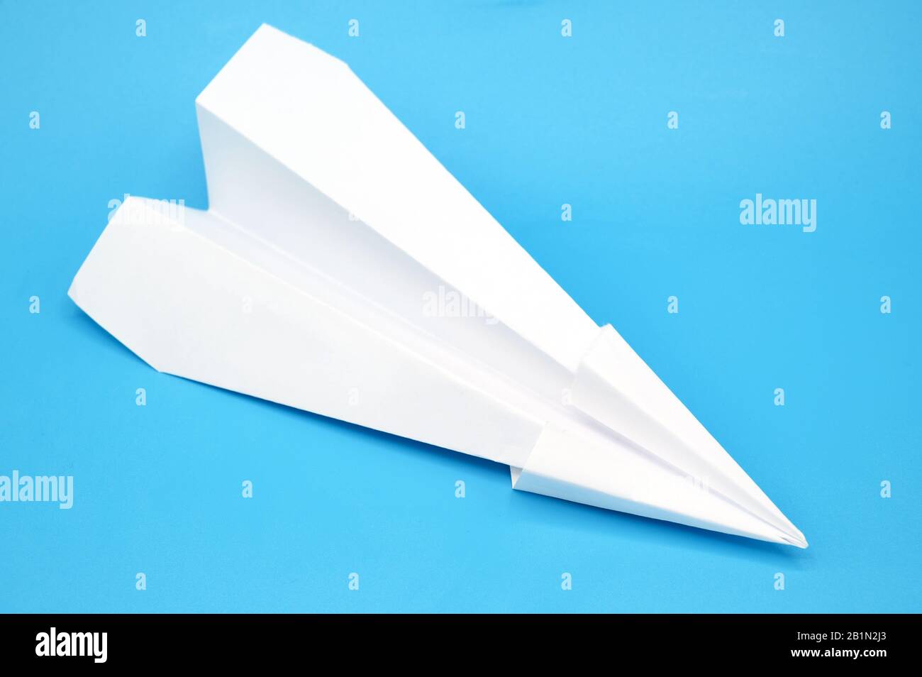 White paper plane on blue background . Stock Photo