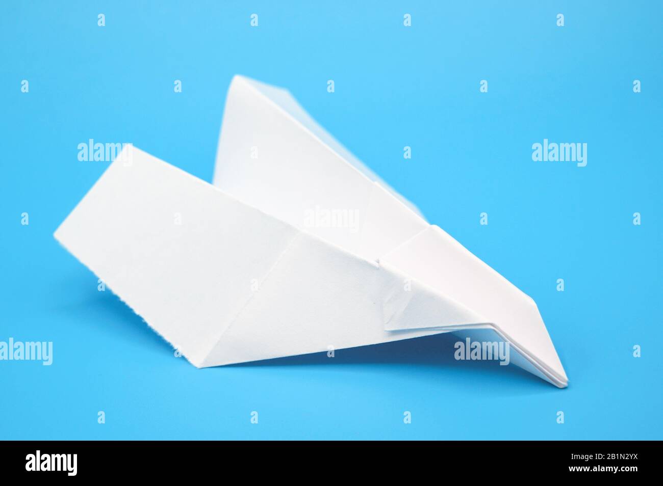 White paper plane on blue background . Stock Photo