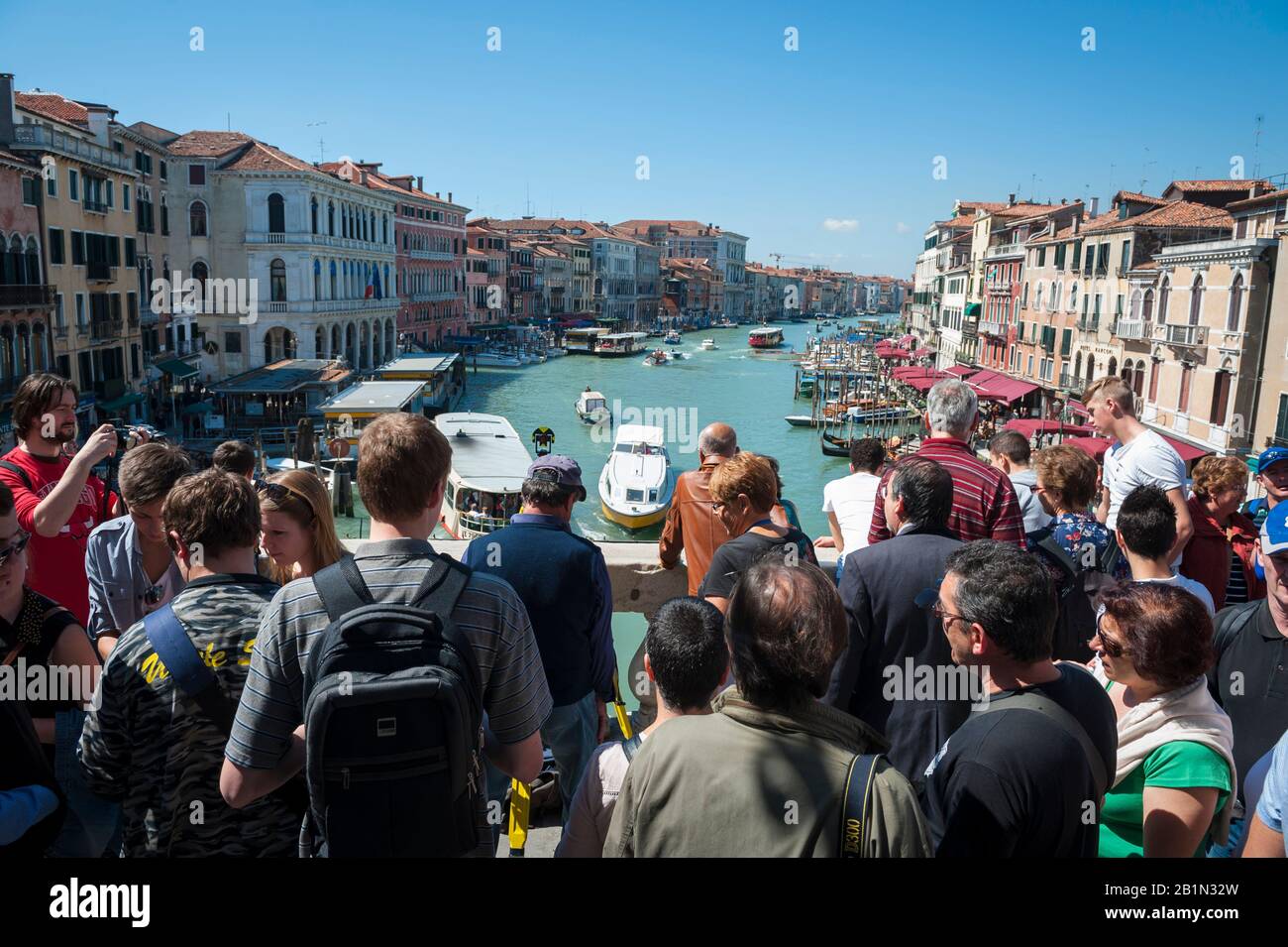 VENICE - MAY 27, 2013: Crowd of tourists jostle for a viewpoint of the Grand Canal on Rialto Bridge, one of the city's most photographed attractions. Stock Photo