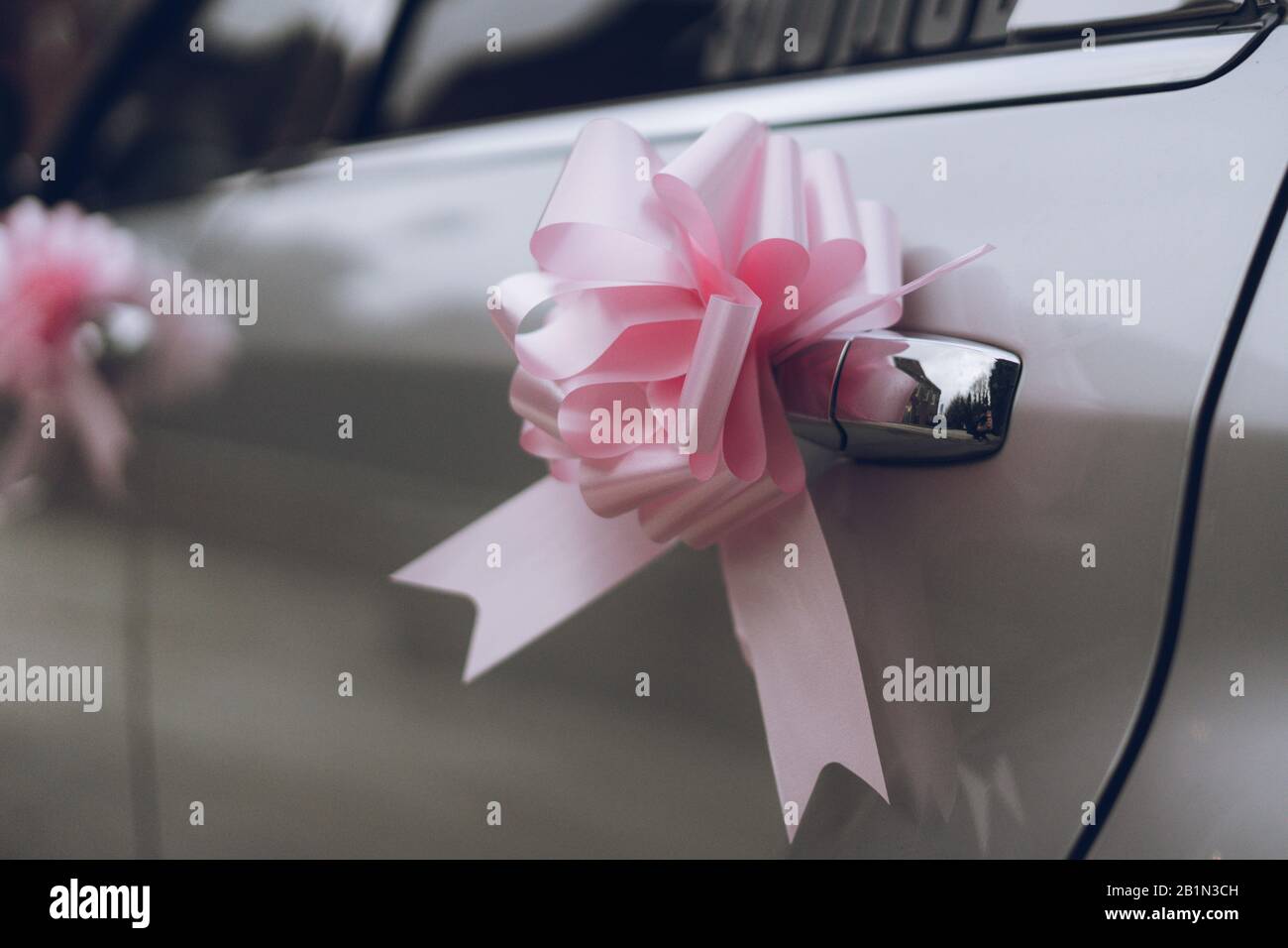 a pink bow made of ribbon on the door handle of a wedding car or wedding limousine Stock Photo