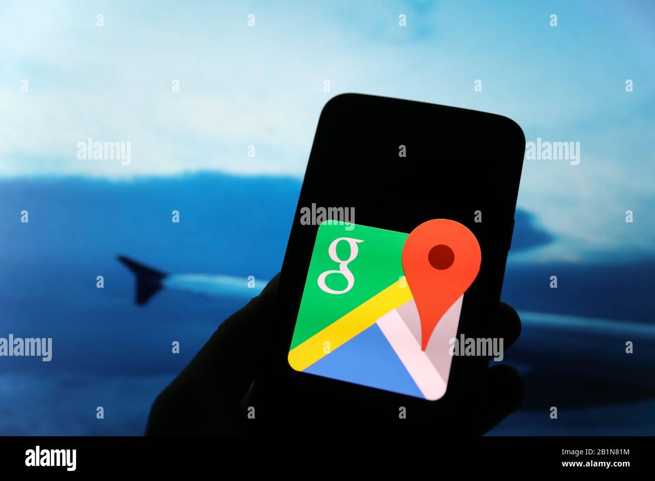 Google logo seen displayed on smart phone screen with a view from the airplane and an airplane wing visible blurred in the background Stock Photo
