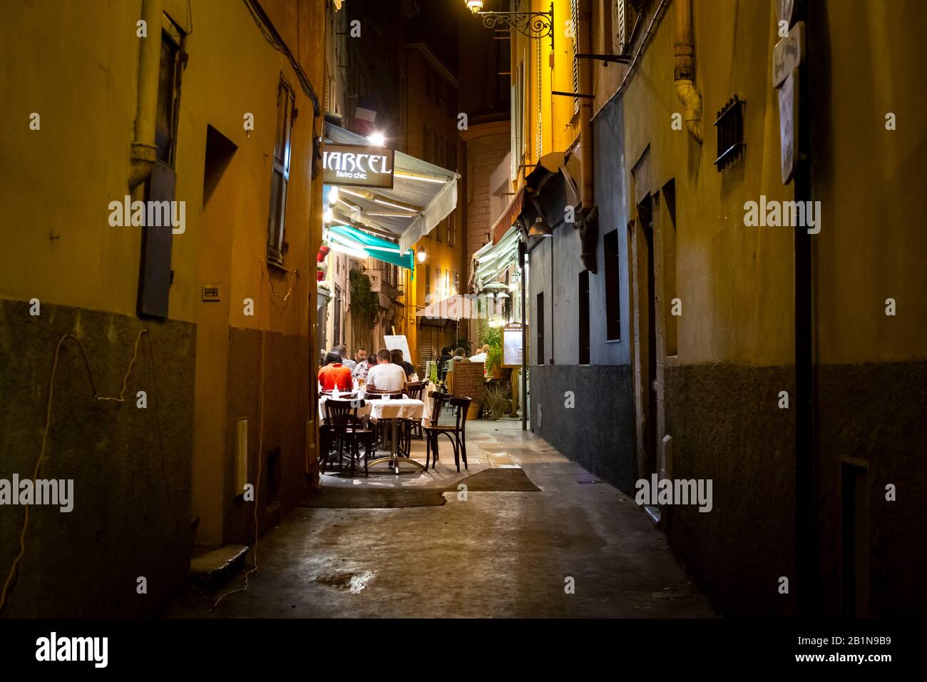 Tourists enjoy a late dinner at a cafe in a narrow alley in the Vieux Nice Old Town of Nice, France, on the French Riviera. Stock Photo