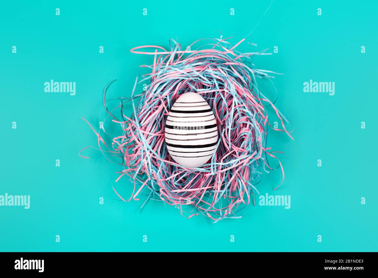 Graphic hand-painted in line egg in decorative nest on blue pastel background. Easter concept. Stock Photo