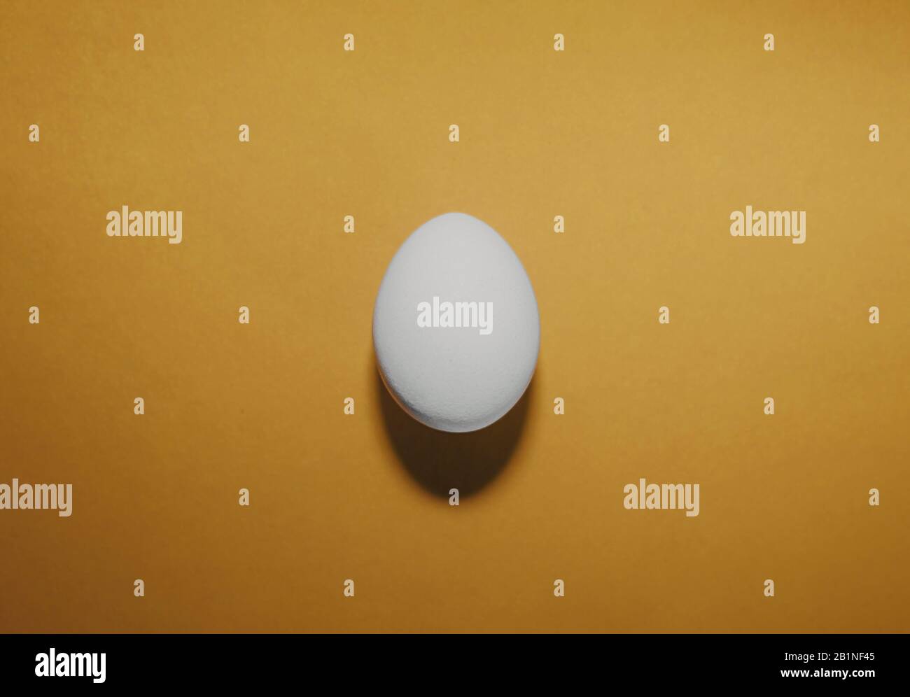 a clean white egg on a flat, clean yellow background. Ready-made layout, trending Easter image of an egg with a hard shadow Stock Photo
