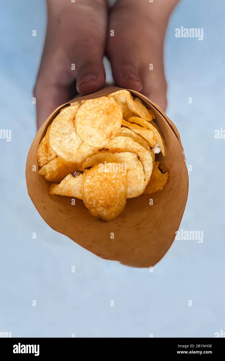 Woman holding a paper cone full of potato chips. Top view. View from