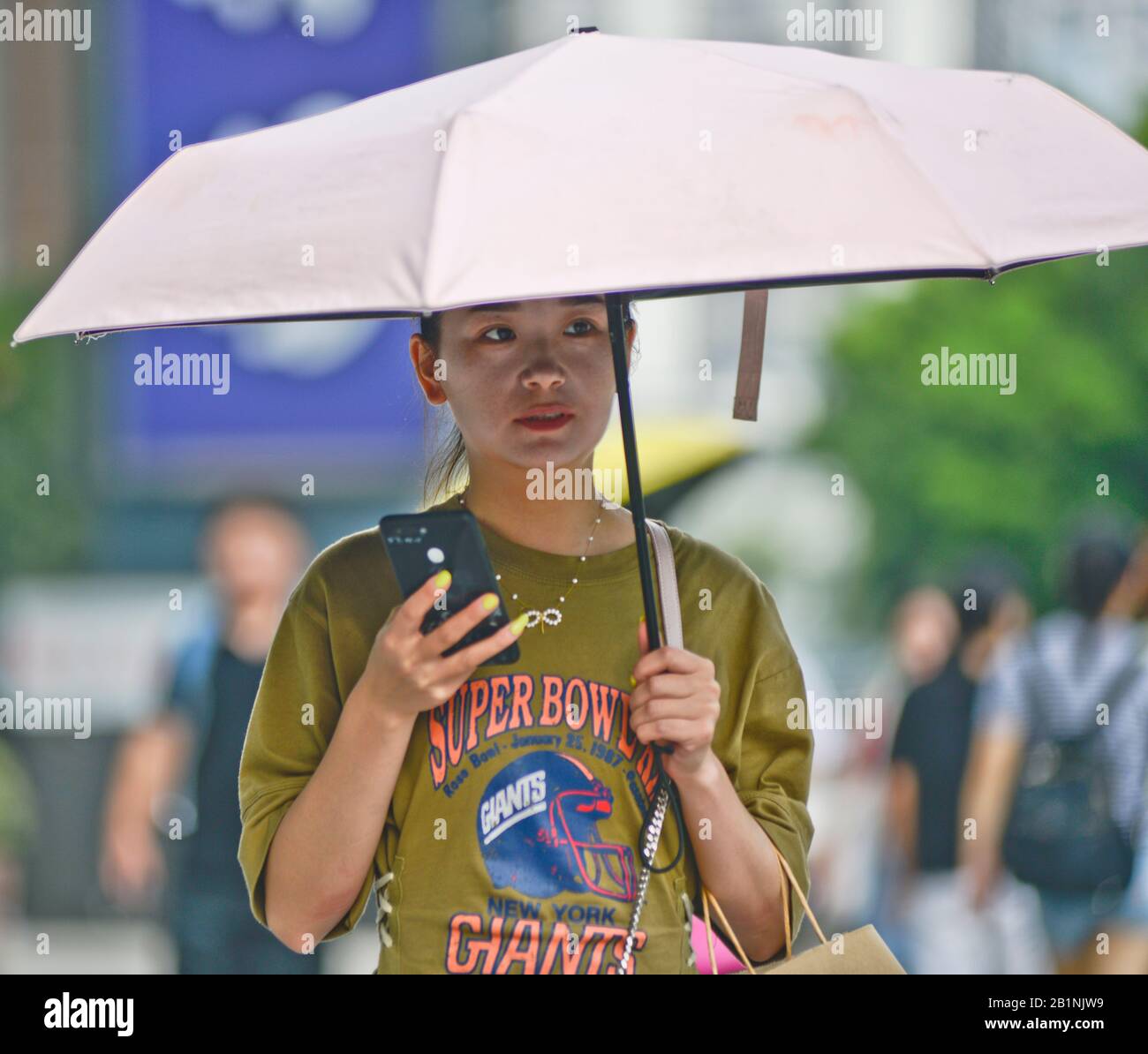 Wuhan: Chinese woman protecting from the sun with an umbrella and white makeup at the exit of Chuhe Hanije metro station, Zhong Bei Lu street. China Stock Photo