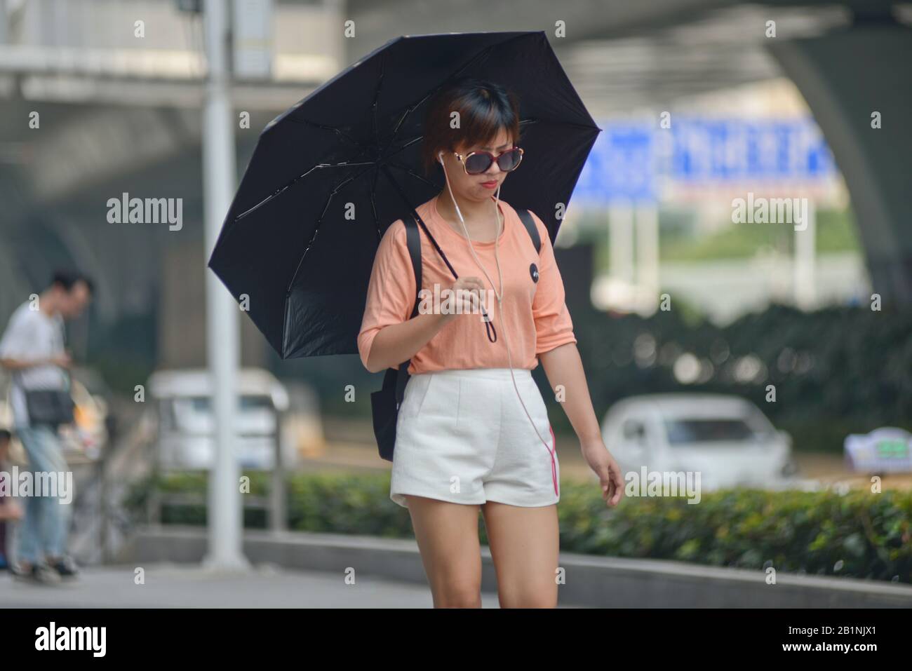 Wuhan: Chinese young woman protecting from the sun with an umbrella at the exit of Chuhe Hanije metro station, Zhong Bei Lu street. China Stock Photo