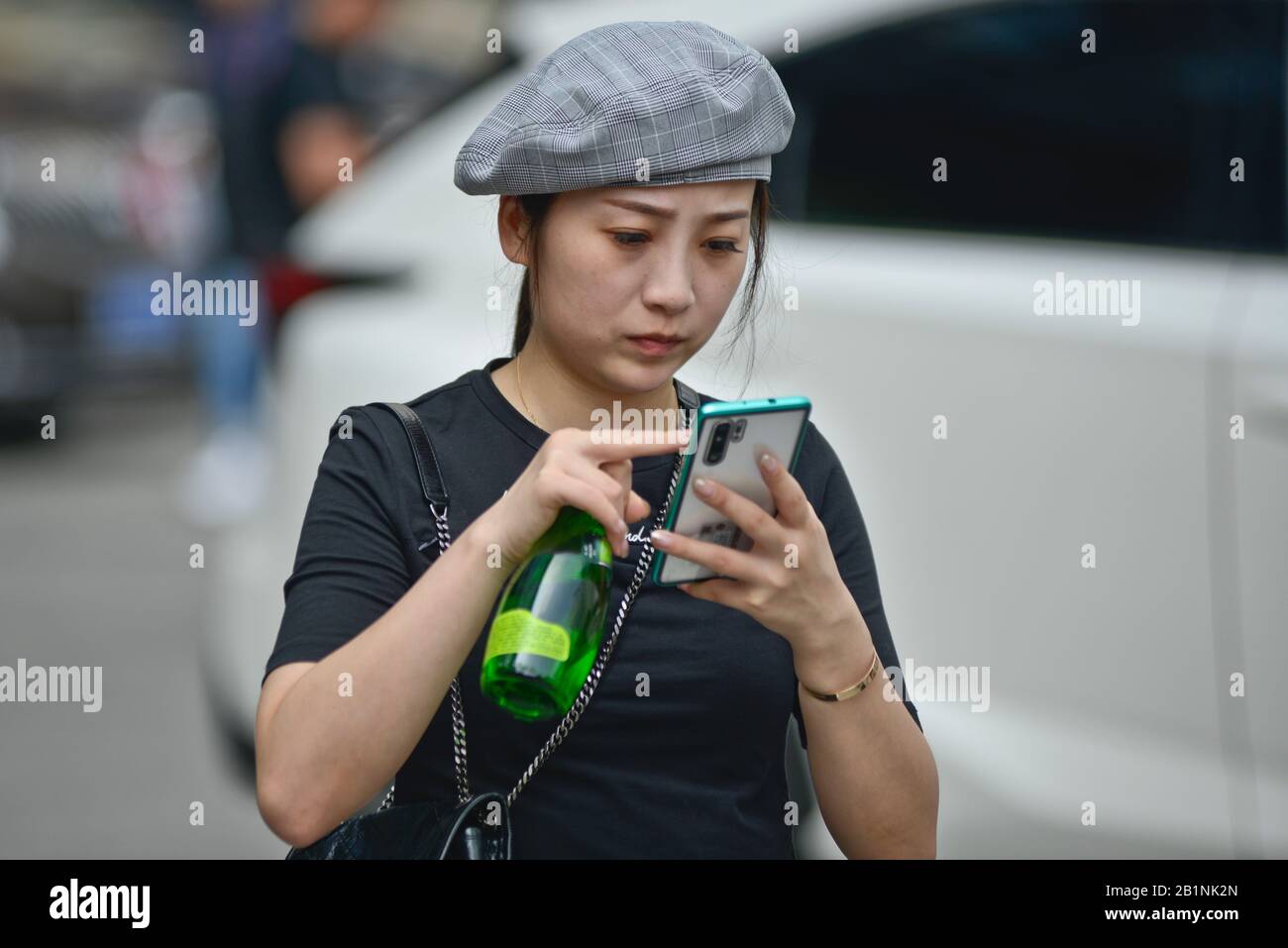 Wuhan: A young chinese girl using her cellphone at the exit of Chuhe Hanije metro station, Zhong Bei Lu street. China Stock Photo
