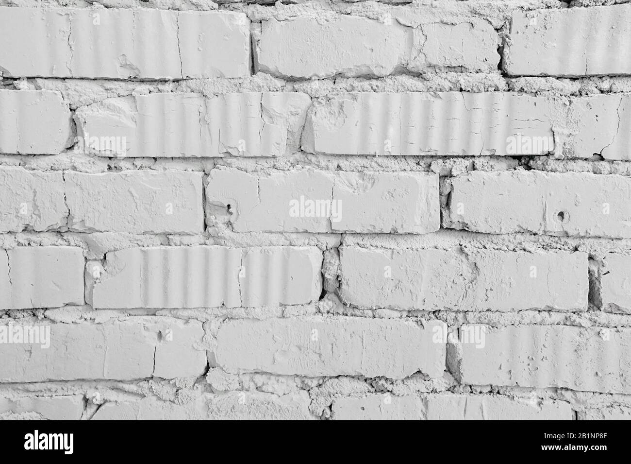 homogeneous background clean white brick wall with cracks from old age