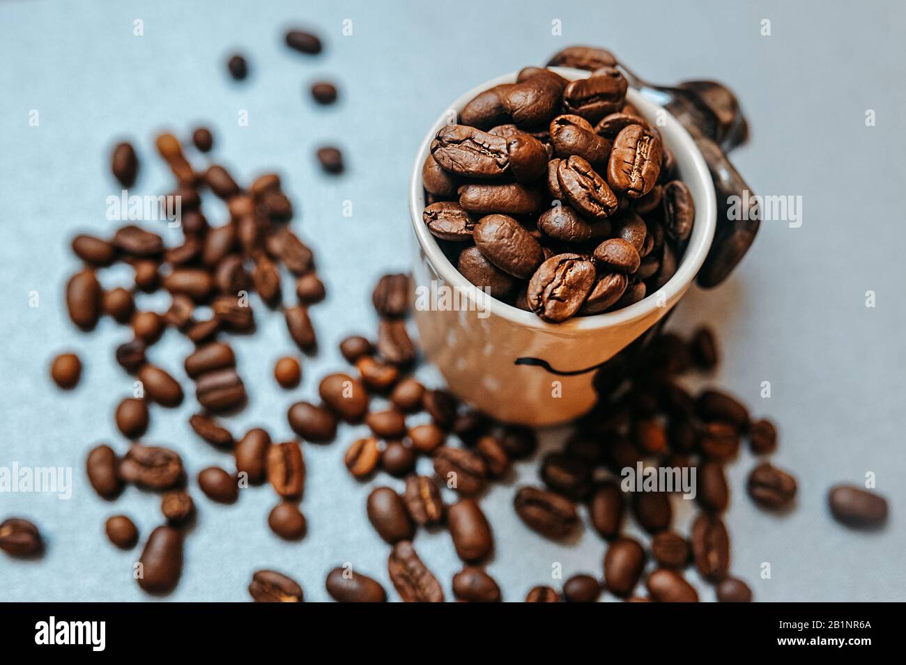 ready-made picture for coffee advertising and ready for publication, a large number of coffee roasted beans are scattered around a white mug full of b Stock Photo