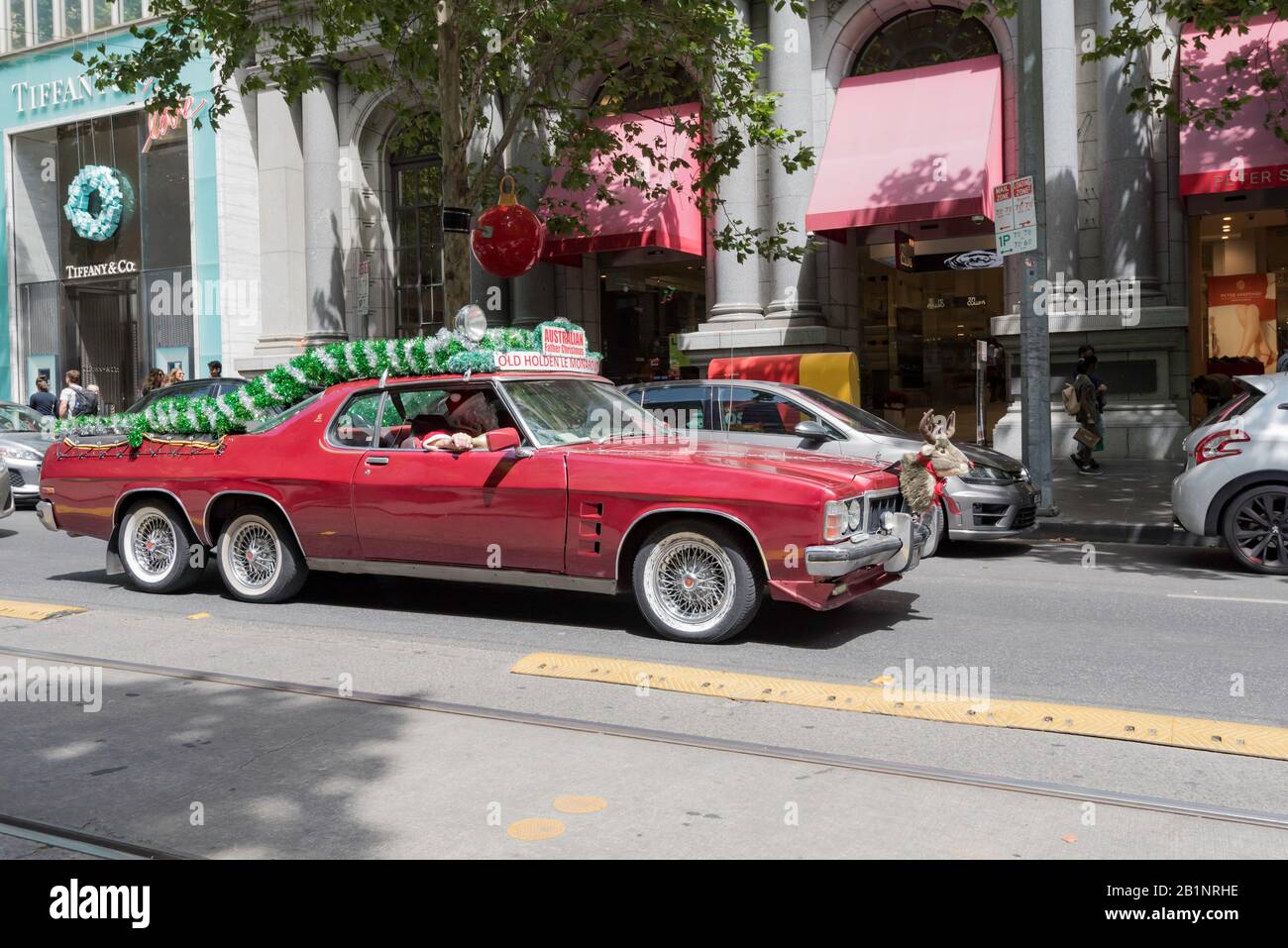 A Holden HQ Monaro converted into a twin axle ute (pickup) with Father Christmas or Santa Clause, driving in Collins St, Melbourne, Australia Stock Photo