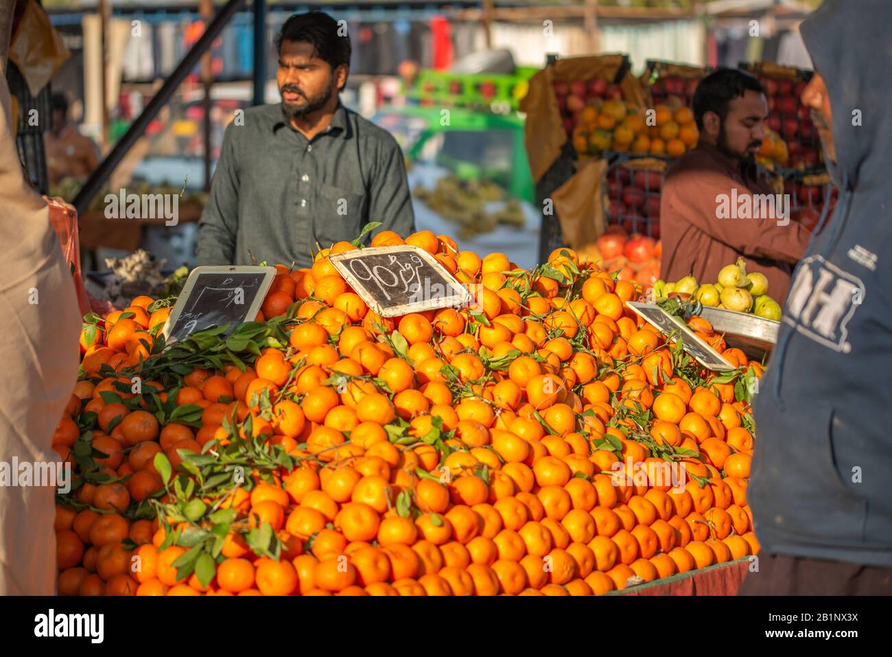 Islamabad, Islamabad Capital Territory, Pakistan - February 3, 2020, A seller is waiting for customers in the vegetable market to sell orange fruits. Stock Photo