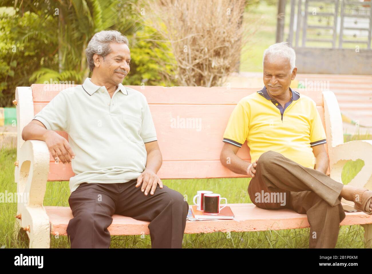 Active retired old men and leisure concept - two senior friends talking outdoor during evening time with coffee - Two elderly brothers having happy Stock Photo