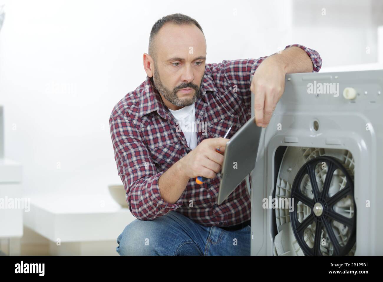 serviceman holding tablet while repairing washing machine Stock Photo