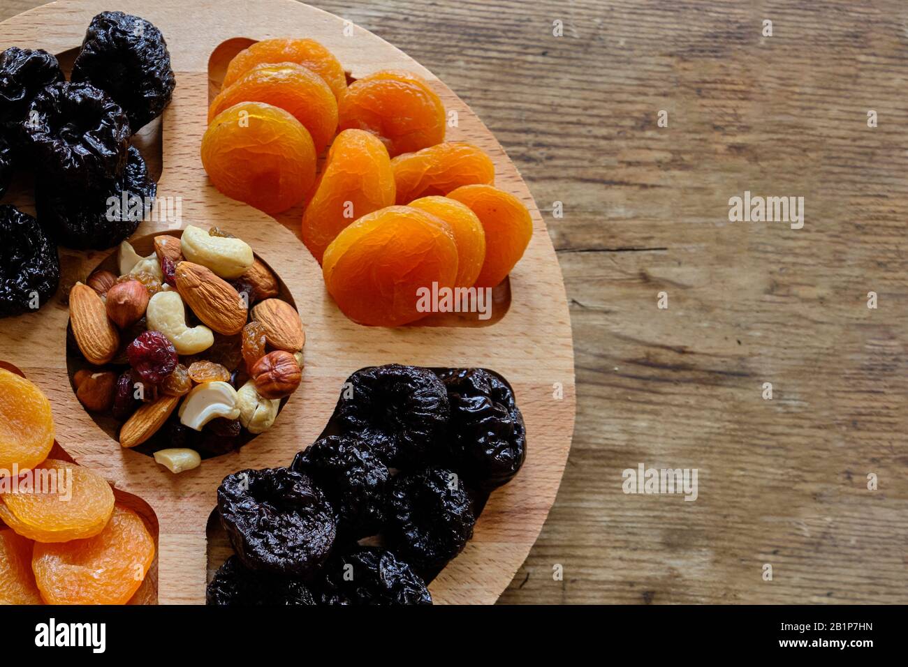 Dried apricots, prunes and nut mix at weathered wooden background Stock