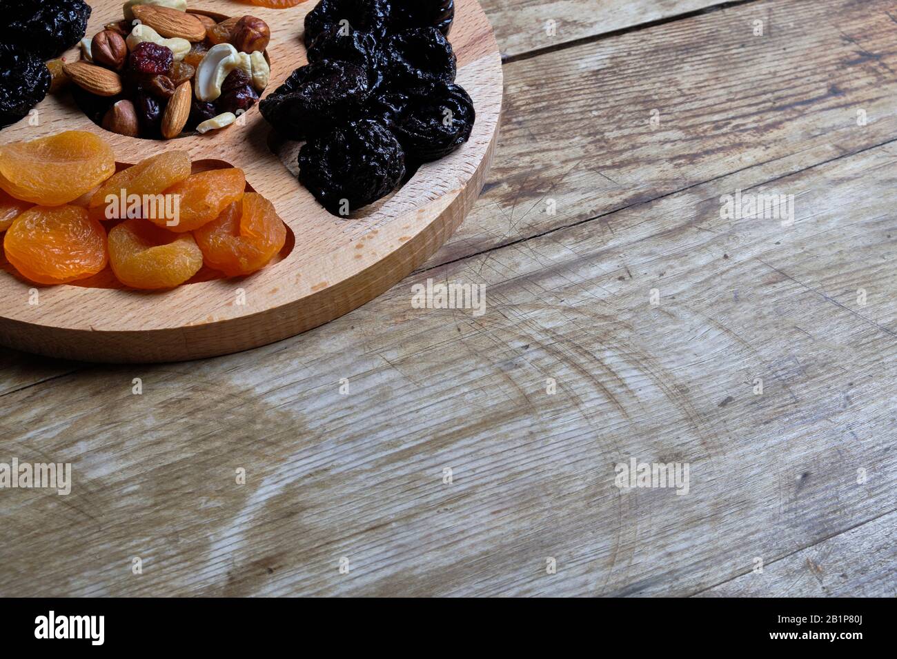 Dried apricots, prunes and nut mix at weathered wooden background Stock