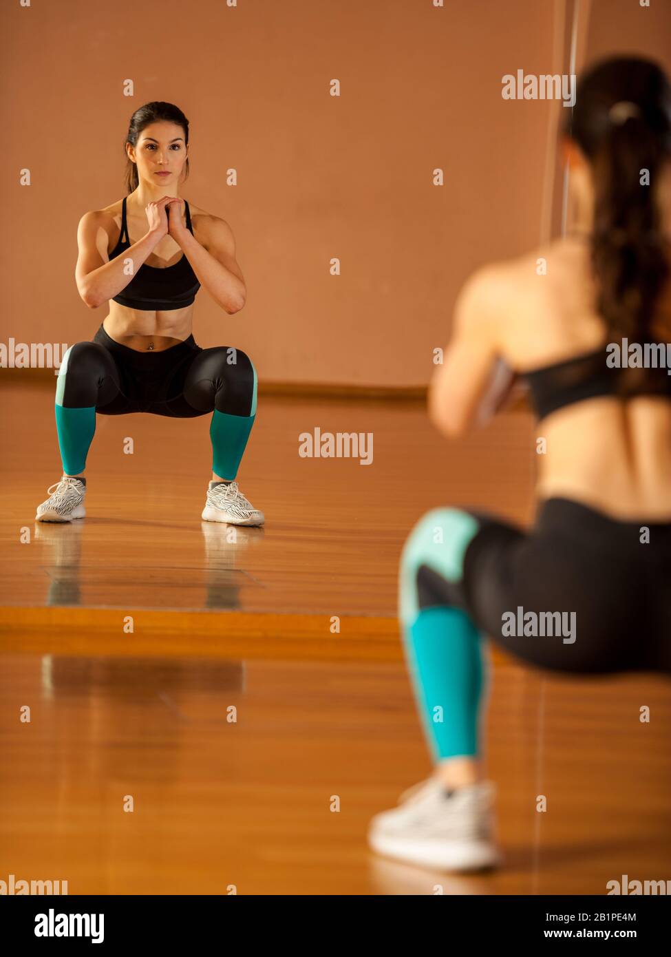 Beautiful fit woman making squats in gym Stock Photo