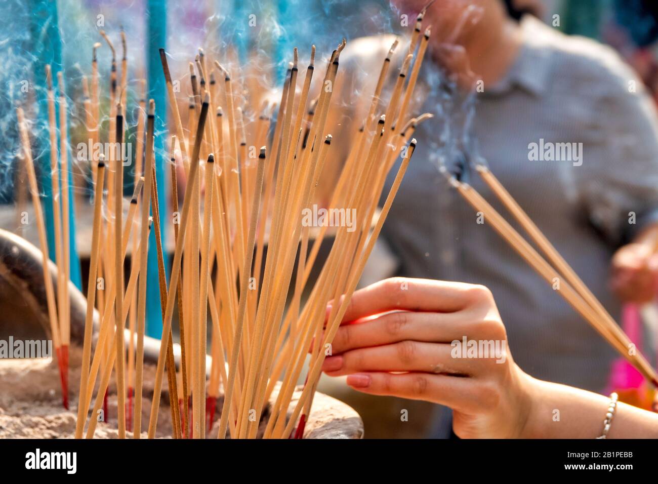 Woman burning incense in Wat Mangkon Kamalawat, Bangkok, Thailand Stock Photo