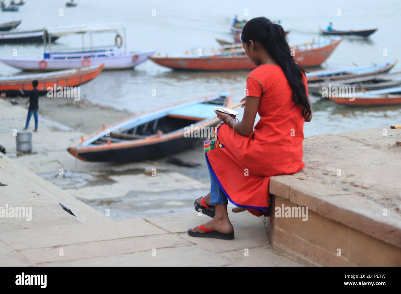 Indian woman is sitting alone on the bank of Ganga River Stock Photo