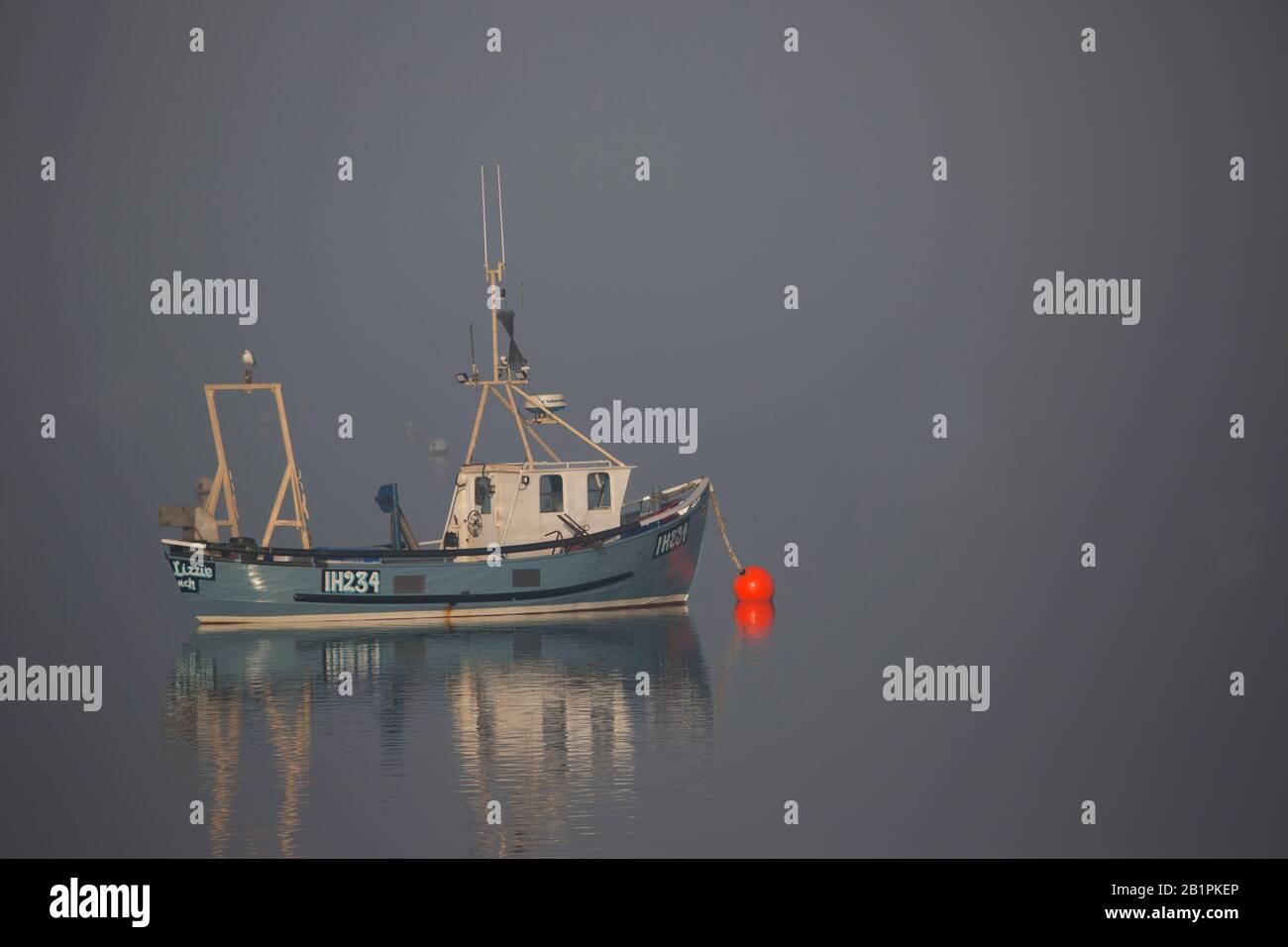 A fishing boat moored in thick fog Stock Photo