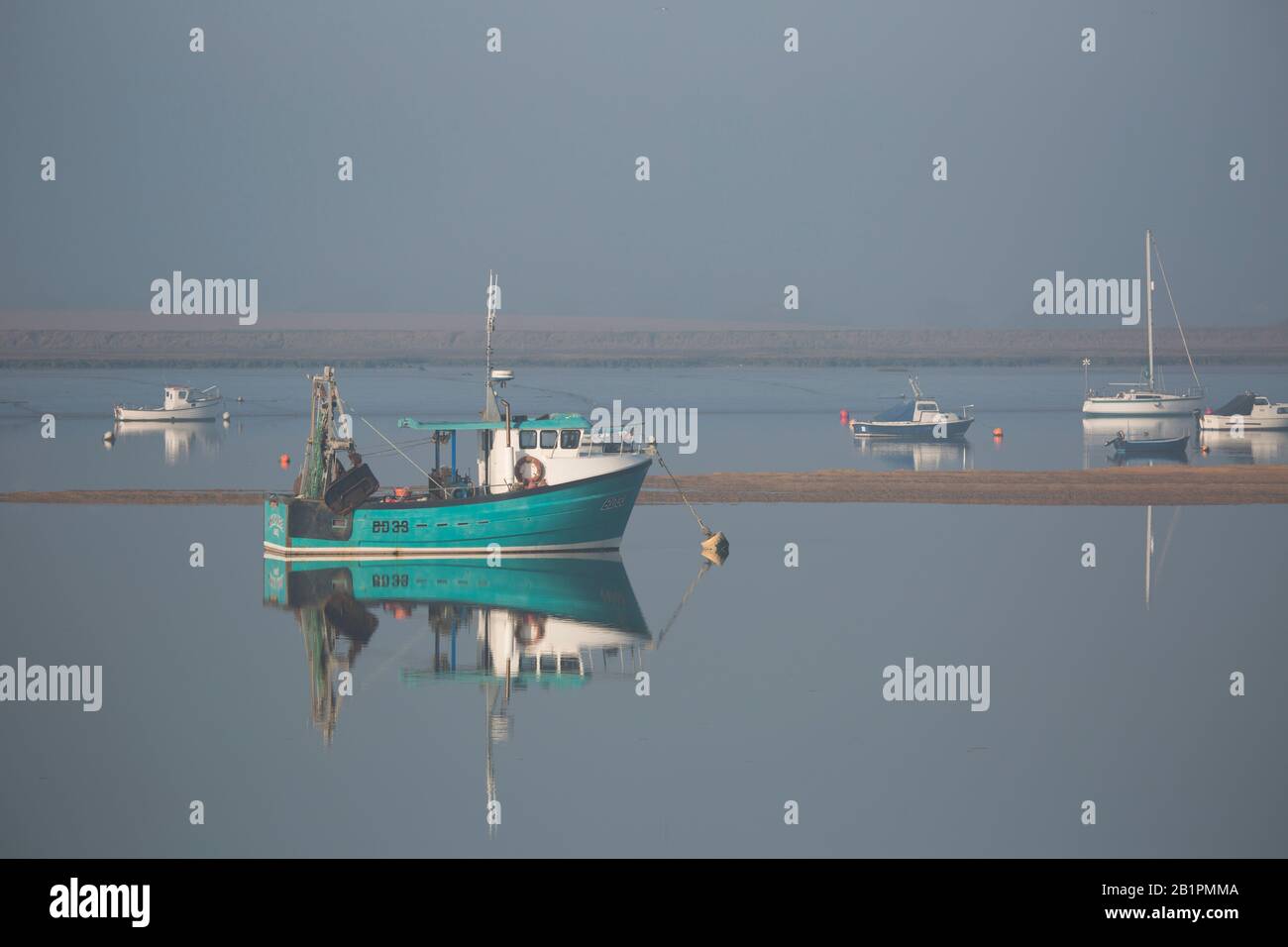 Fishing boats at anchor in the morning fog on an estuary Stock Photo