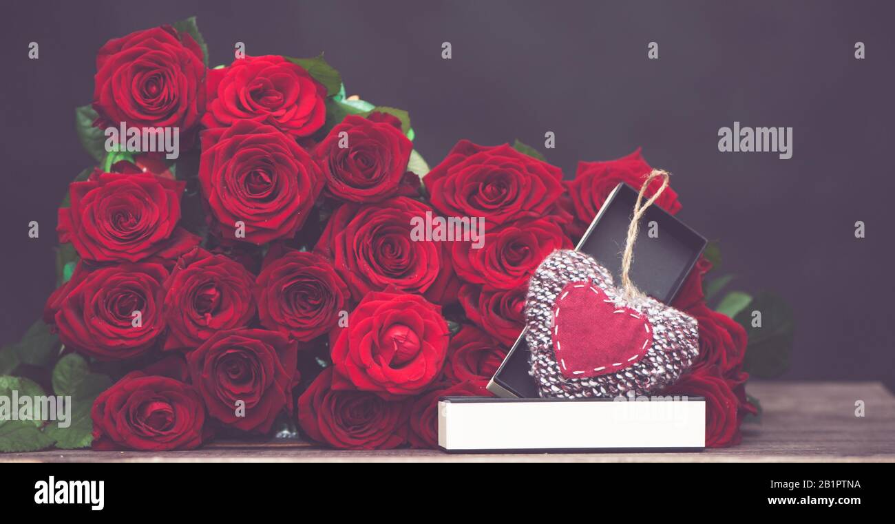 Concept of a gift for Valentine's Day.  large bunch of red roses and an open box with a stylish, knitted heart Stock Photo