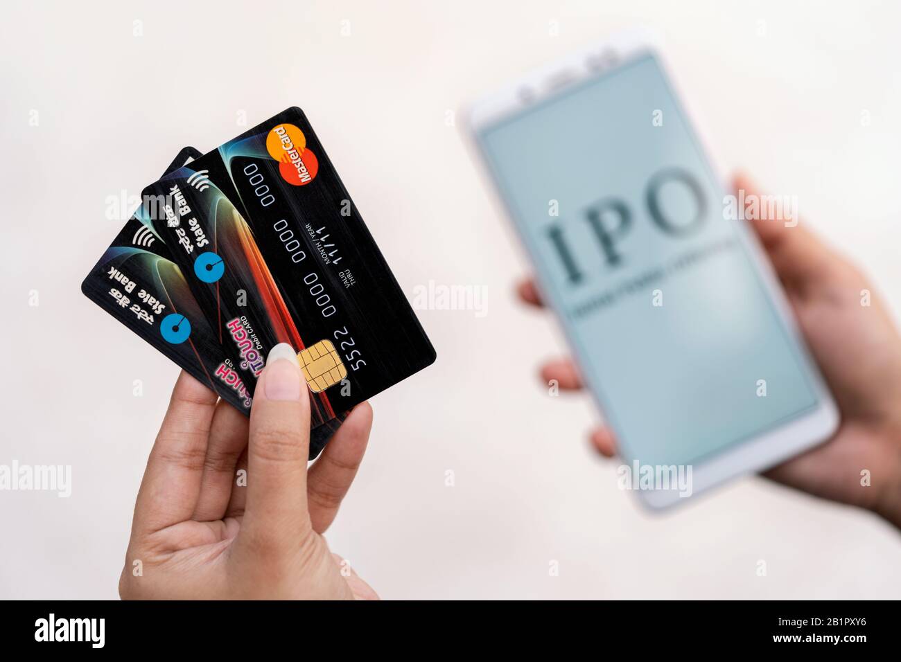 SBI Cards IPO background. Young female hand holding State Bank Of India's ATM or Debit Cards & applying for upcoming Initial Public Offering on her mo Stock Photo