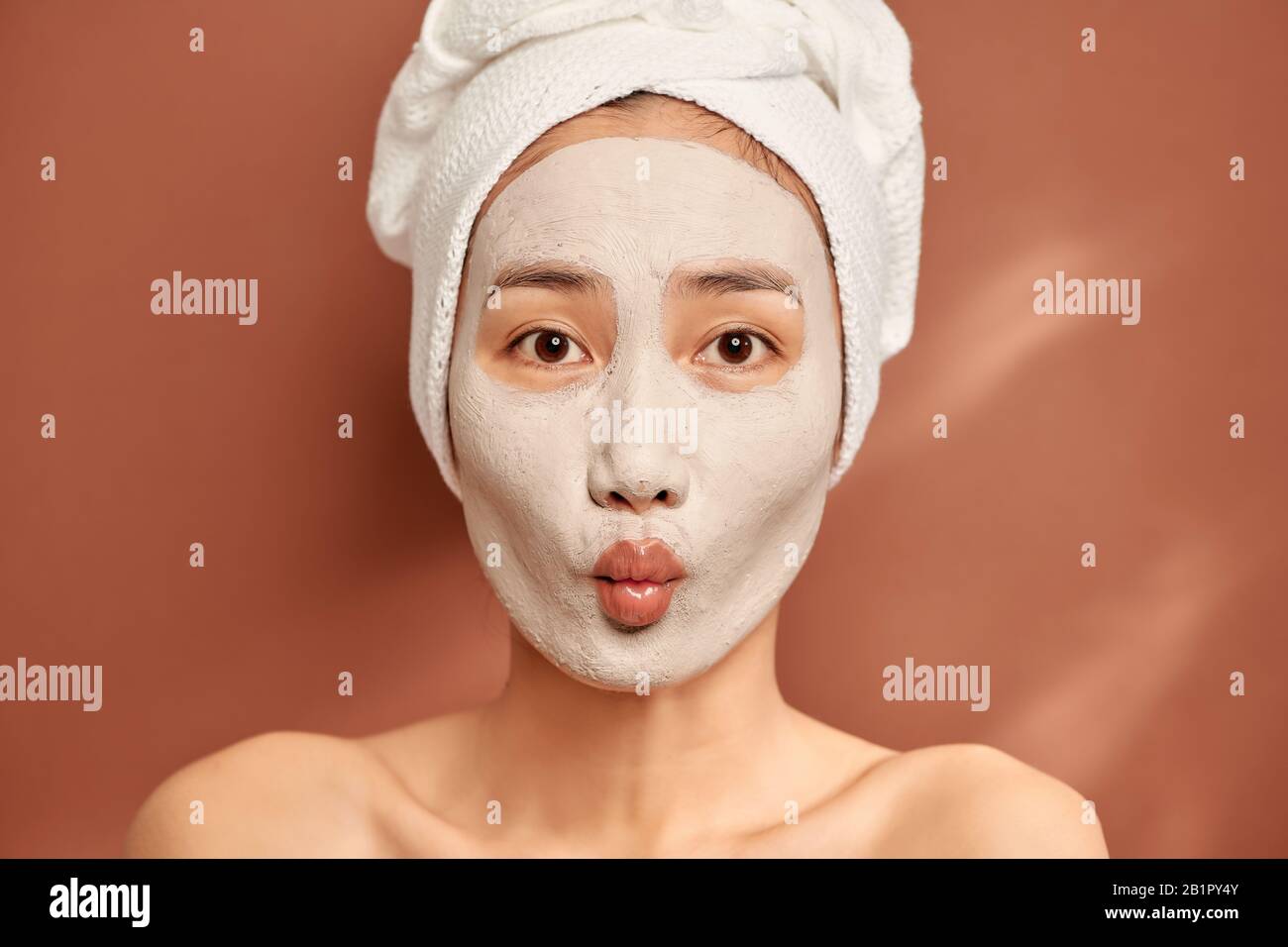 Young beautiful woman with clay face mask. Spa treatment, self care and healthy skin Stock Photo