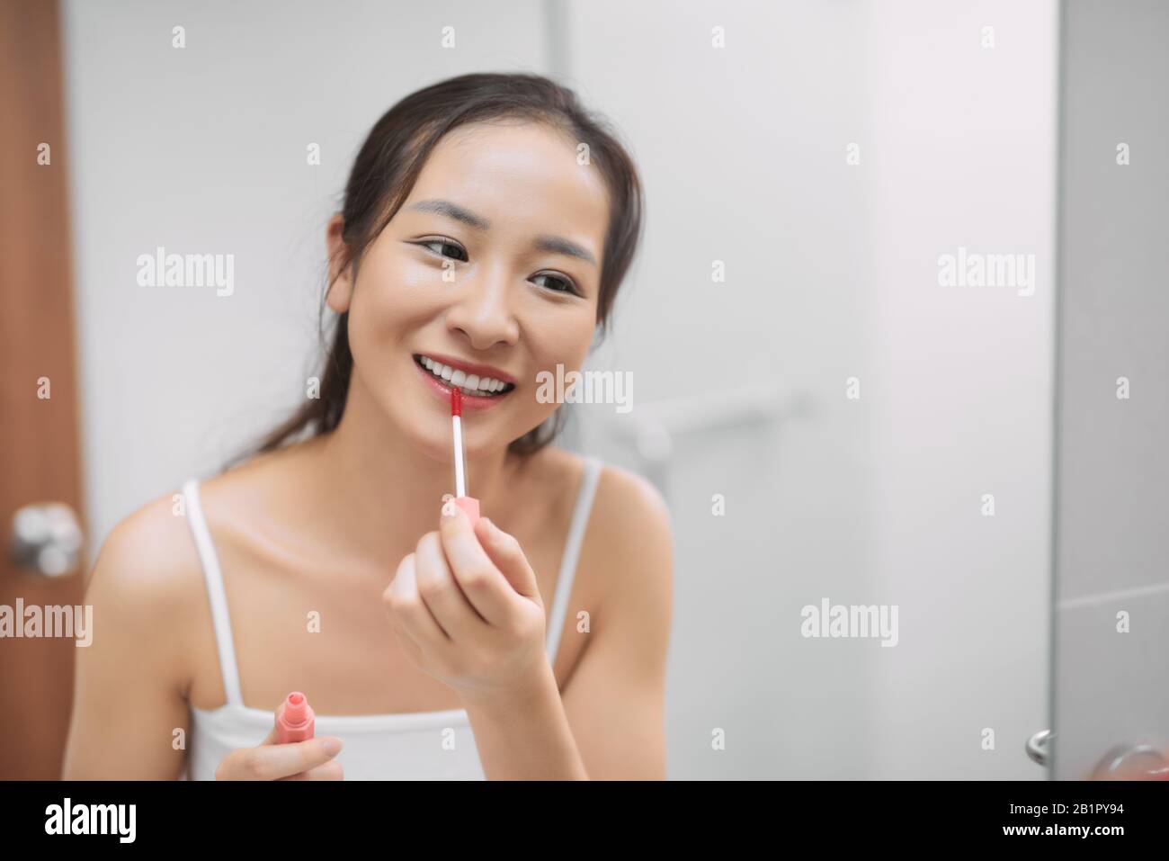 Beautiful Asian woman looking mirror and apply lip make up lipstick in powder room bathroom toilet Stock Photo