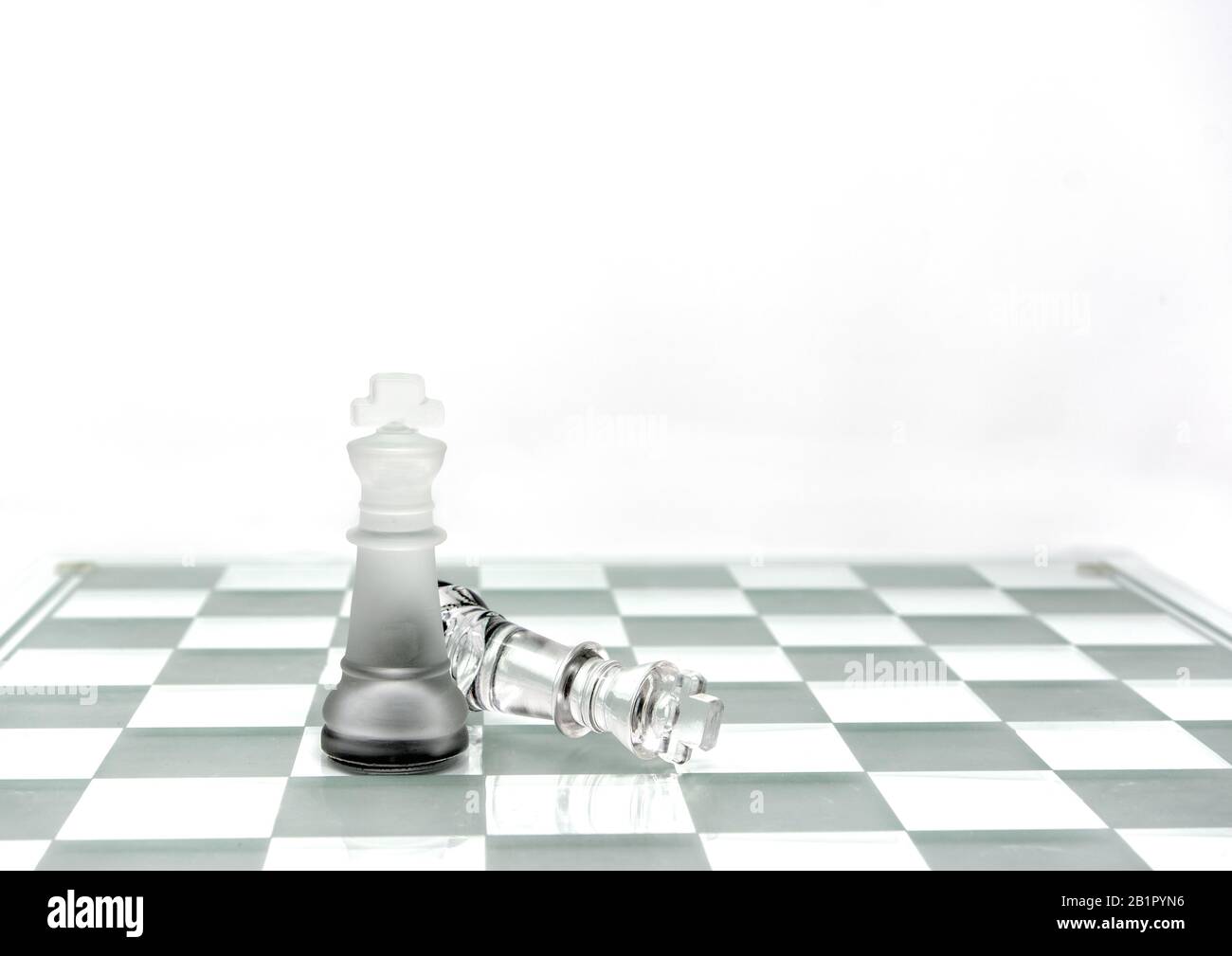 Two King chess pieces on a board in grey Stock Photo