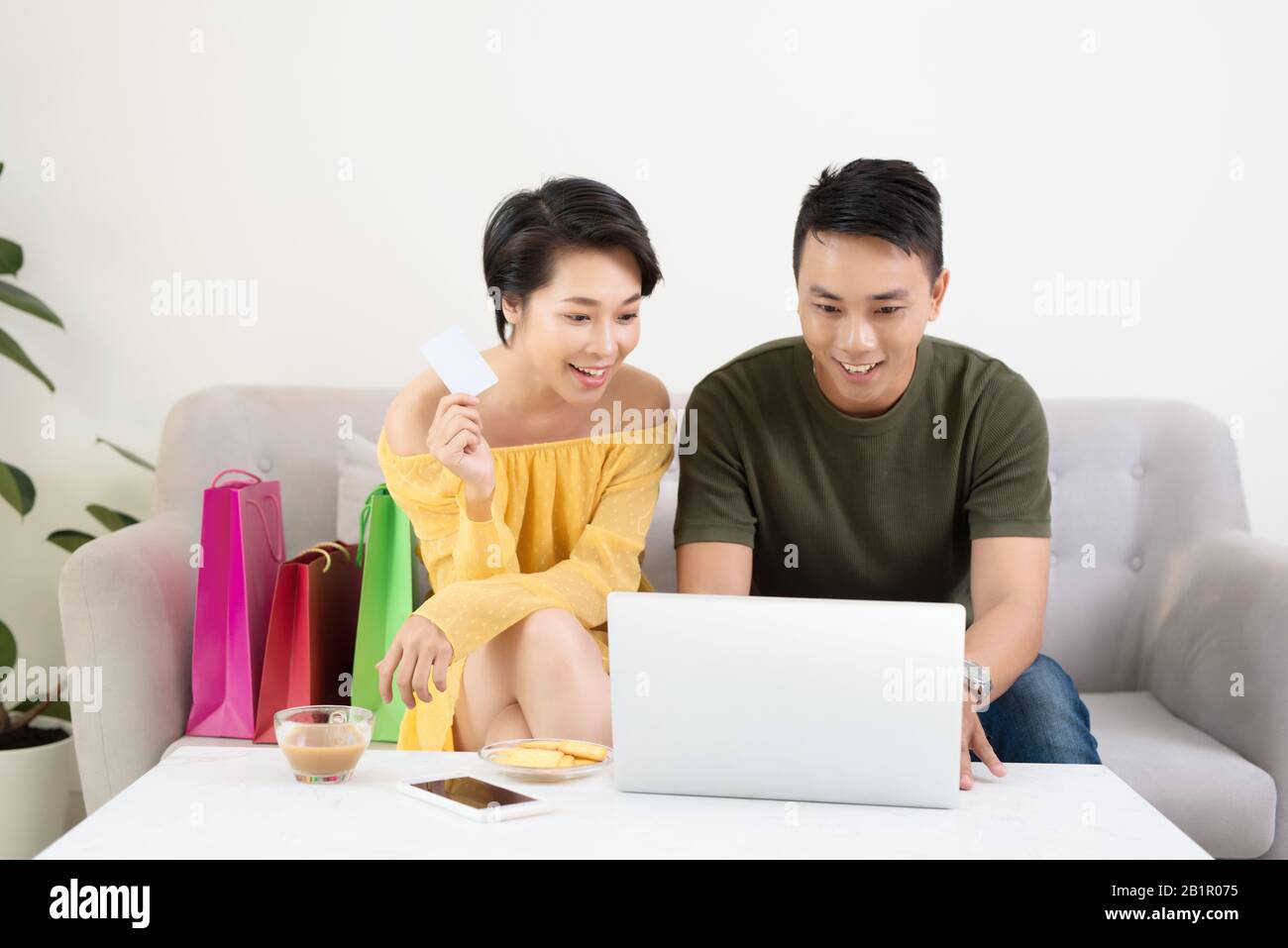 Young Asian Couple Making Online Purchases On Laptop At Home Stock Photo
