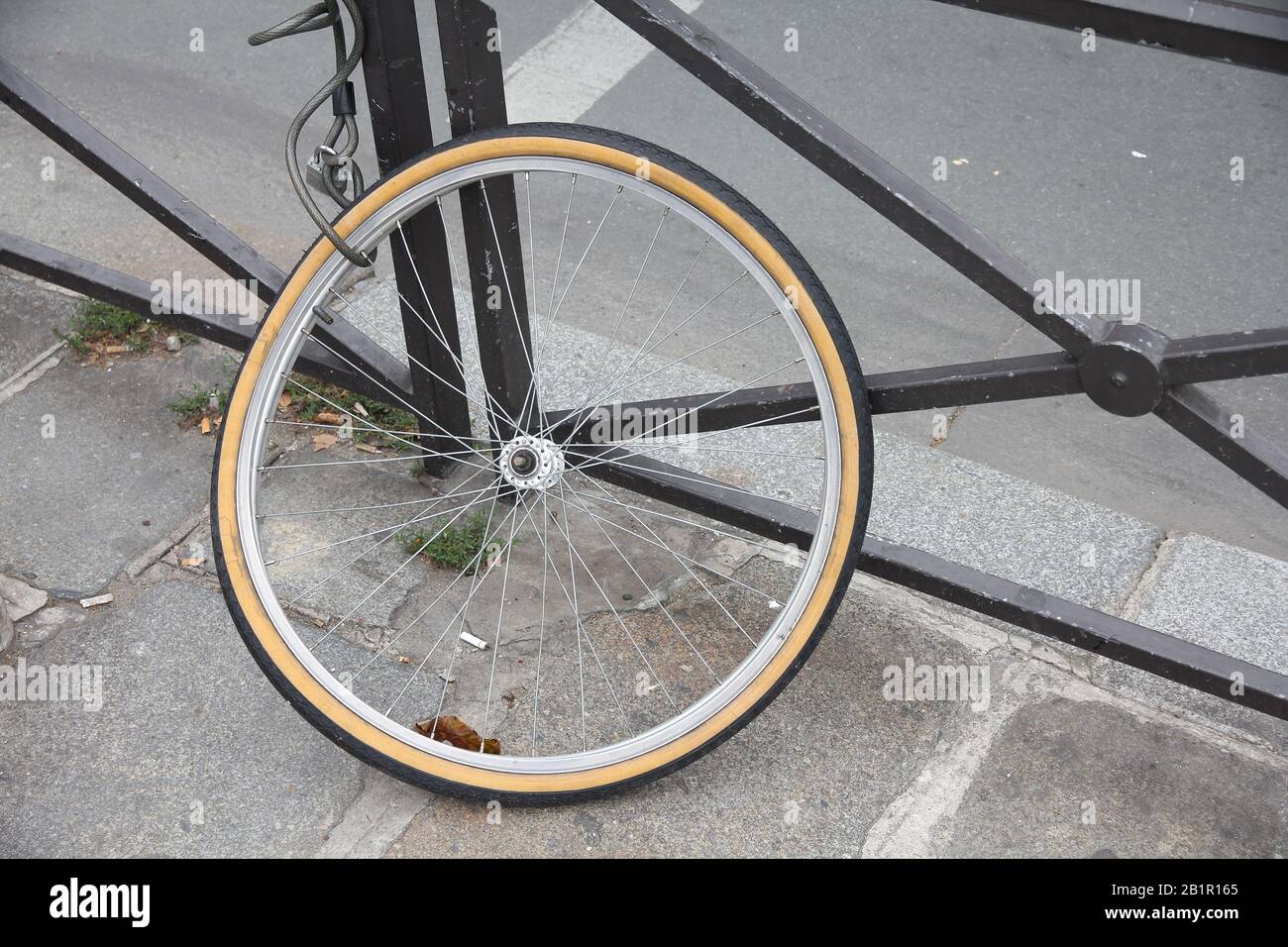 Stolen bicycle front wheel locked to a city railing in Paris, France