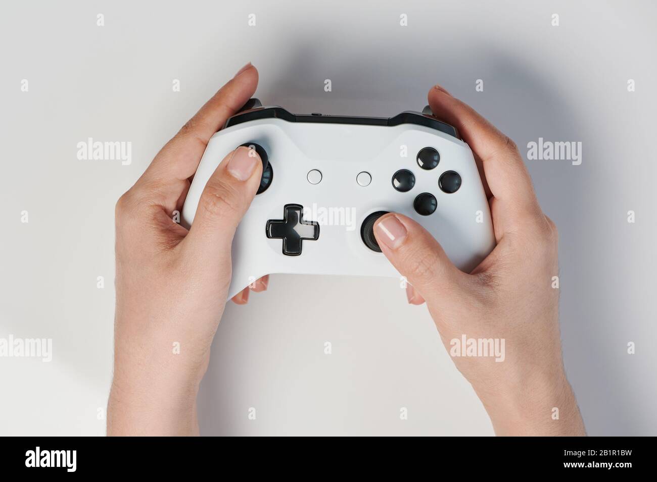 White controller with black buttons in hand above top view Stock Photo