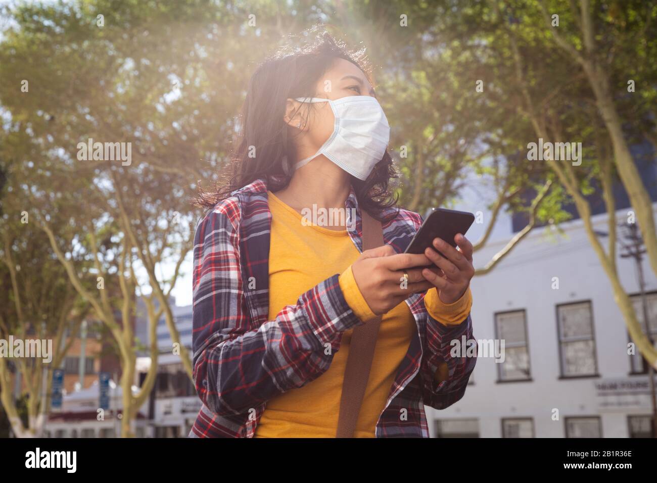 Woman wearing a Corona Virus face mask and using her phone Stock Photo