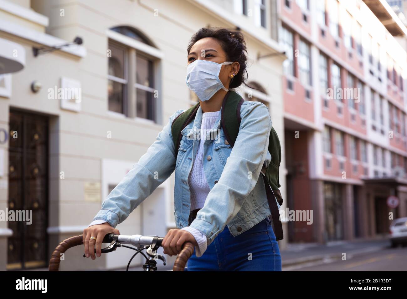 Woman biking in the street and wearing a Corona Virus face mask Stock Photo