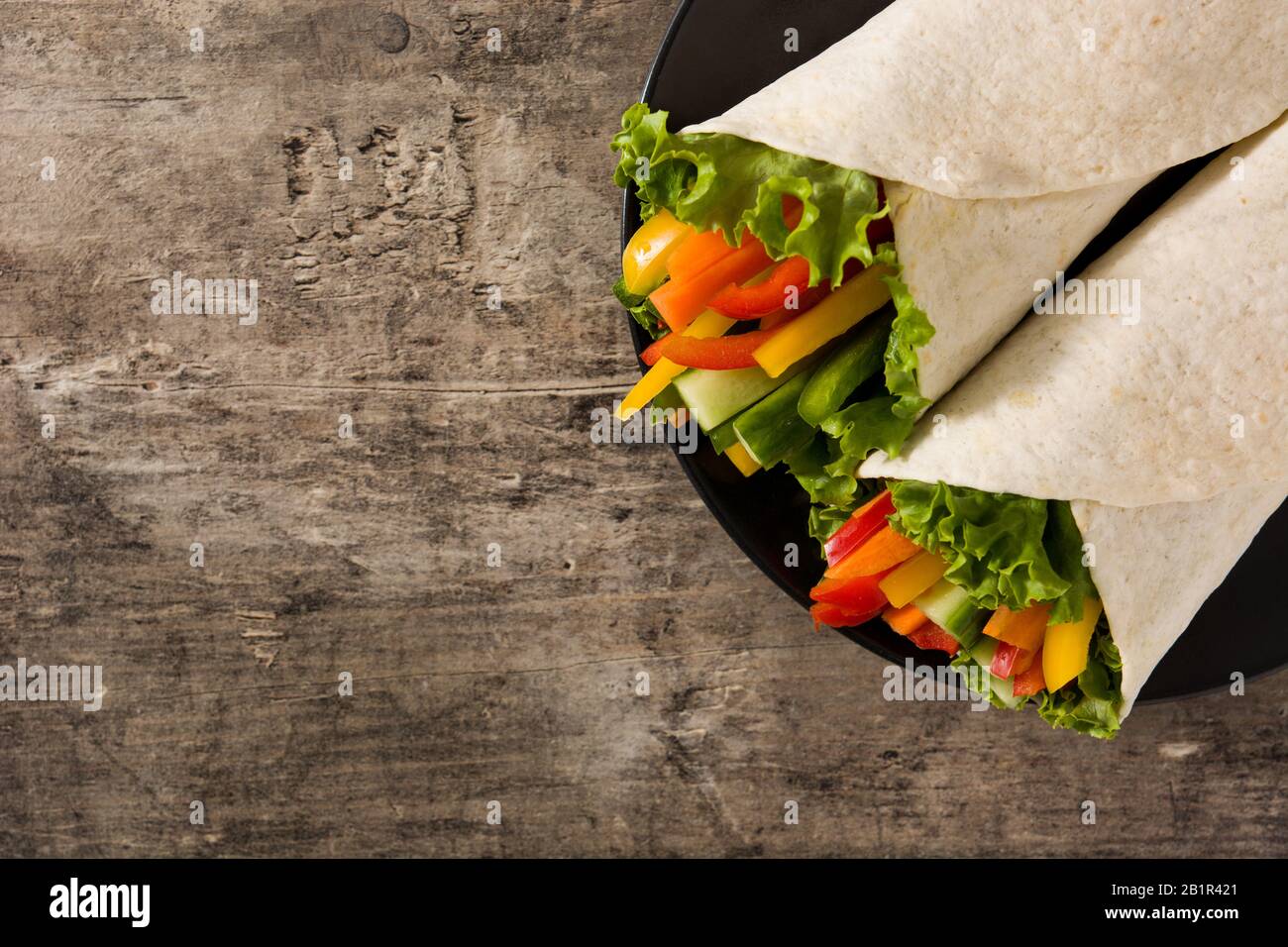 Vegetable tortilla wraps on wooden table. Top view. Copy space Stock
