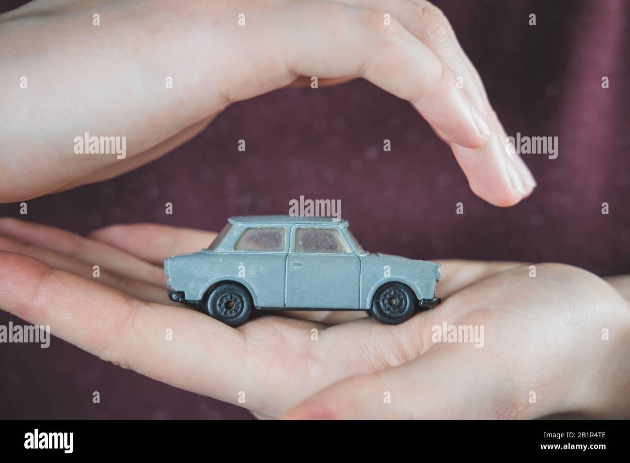 Toy car in human hands. Concept of car safety, vehicle insurance plans