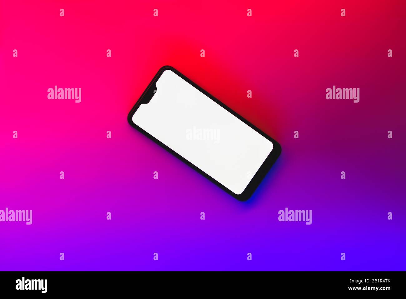Modern generic smartphone in neon backdrop. Cellphone with white screen in vibrant blue and red background Stock Photo