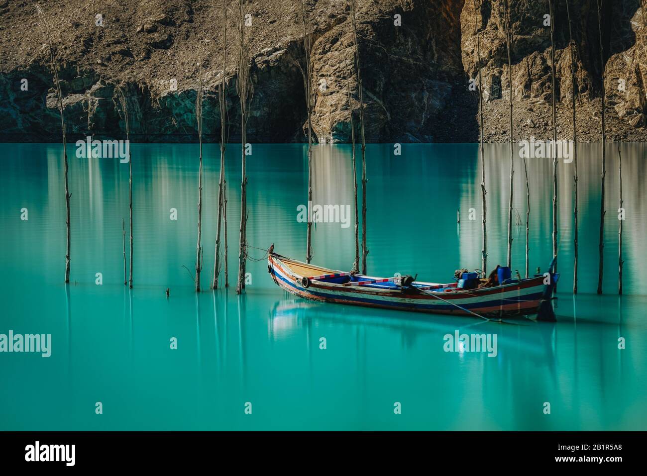 Boat with reflections moored in the turquoise blue water of Attabad Lake, Gojal Valley, Hunza, Gilgit Baltistan, Pakistan formed after the 2010 Attaba Stock Photo