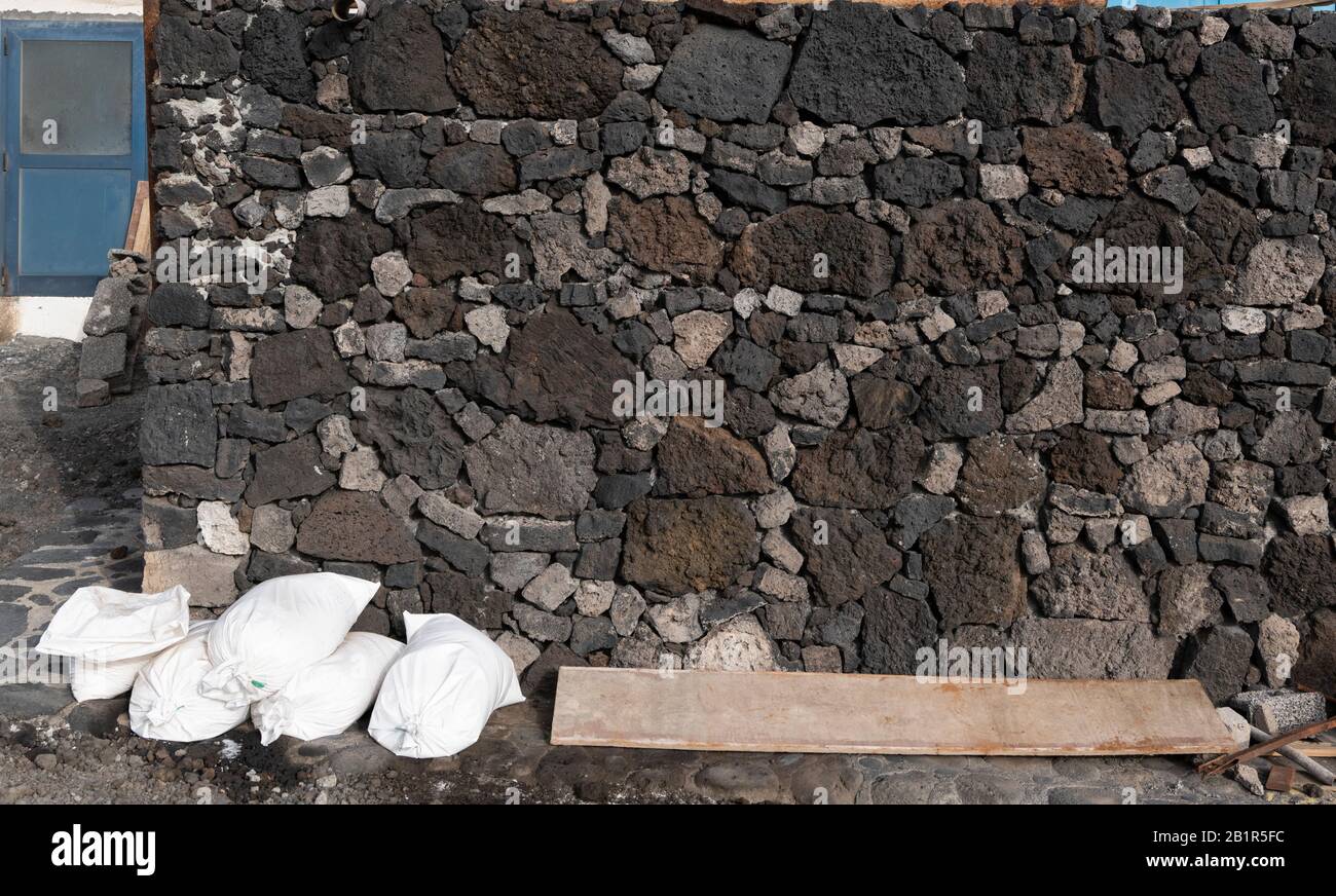 Large bags of seasalt stacked against a wall made of blocks of vesicular basalt lava in Salinas de Fuencaliente, southern La Palma, Canary islands Stock Photo
