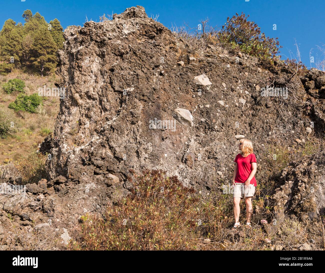 A female tourist standing beside a volcaniclastic deposit with a mixture of  clasts of various sizes and types above the village of Jedey, La Palma Stock Photo