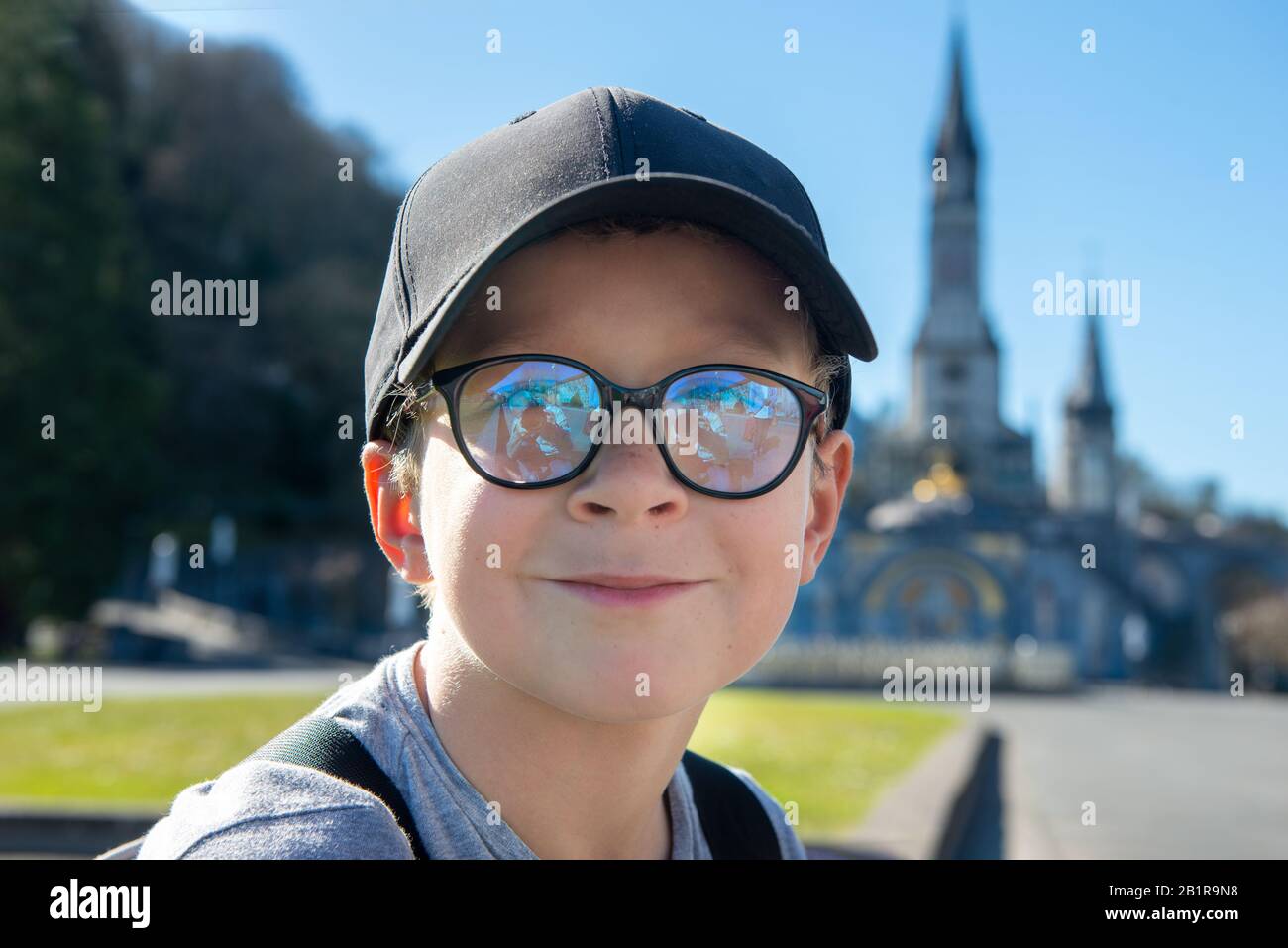 a young boy with the cathedralsanctuary of Lourdes (France Stock Photo