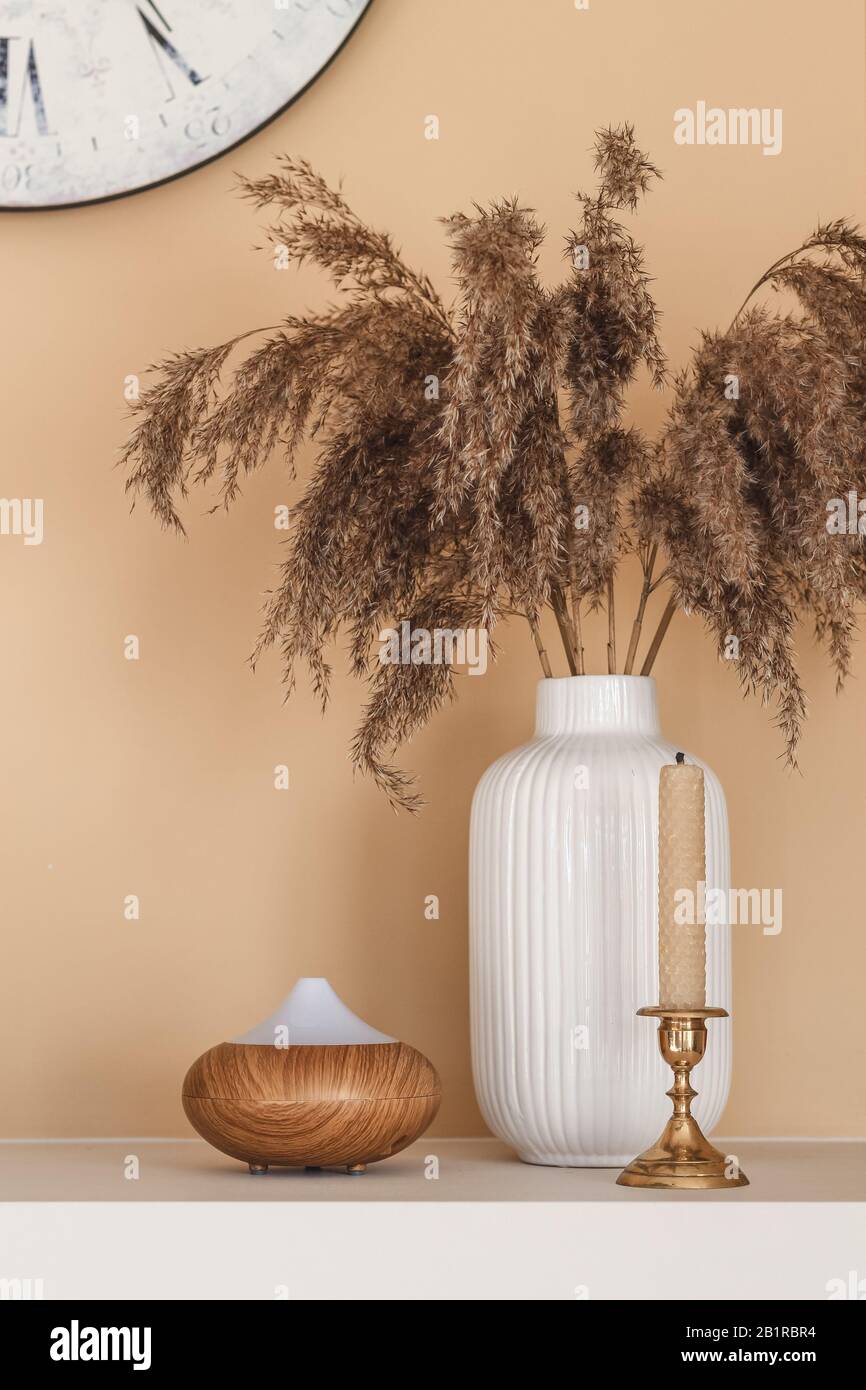 Natural interior decor. Still life composition with reeds, bee wax candle and essential oil diffuser Stock Photo