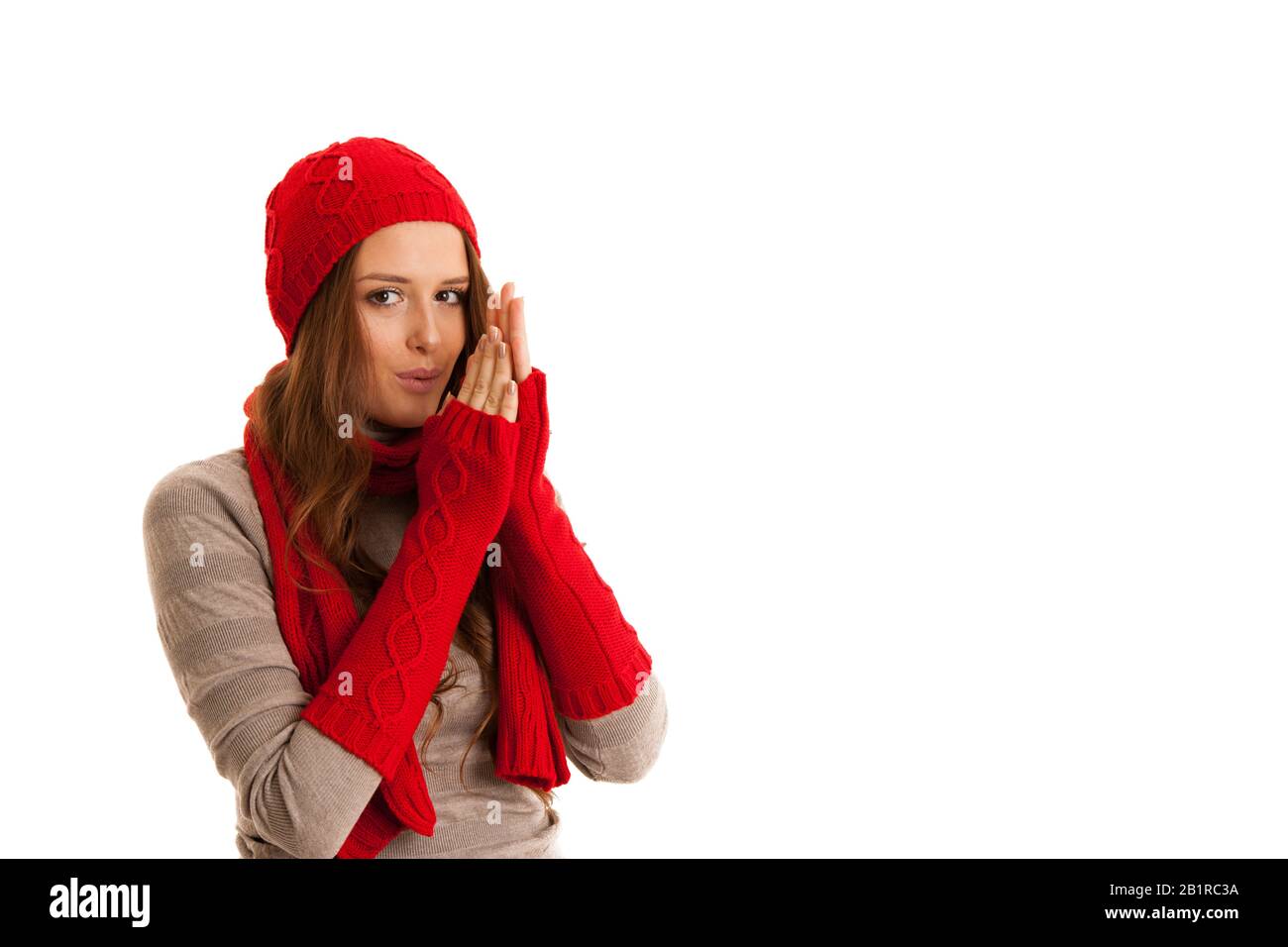 Beautiful young woman in sweater, hat and scarf gestures cold temperatures Stock Photo