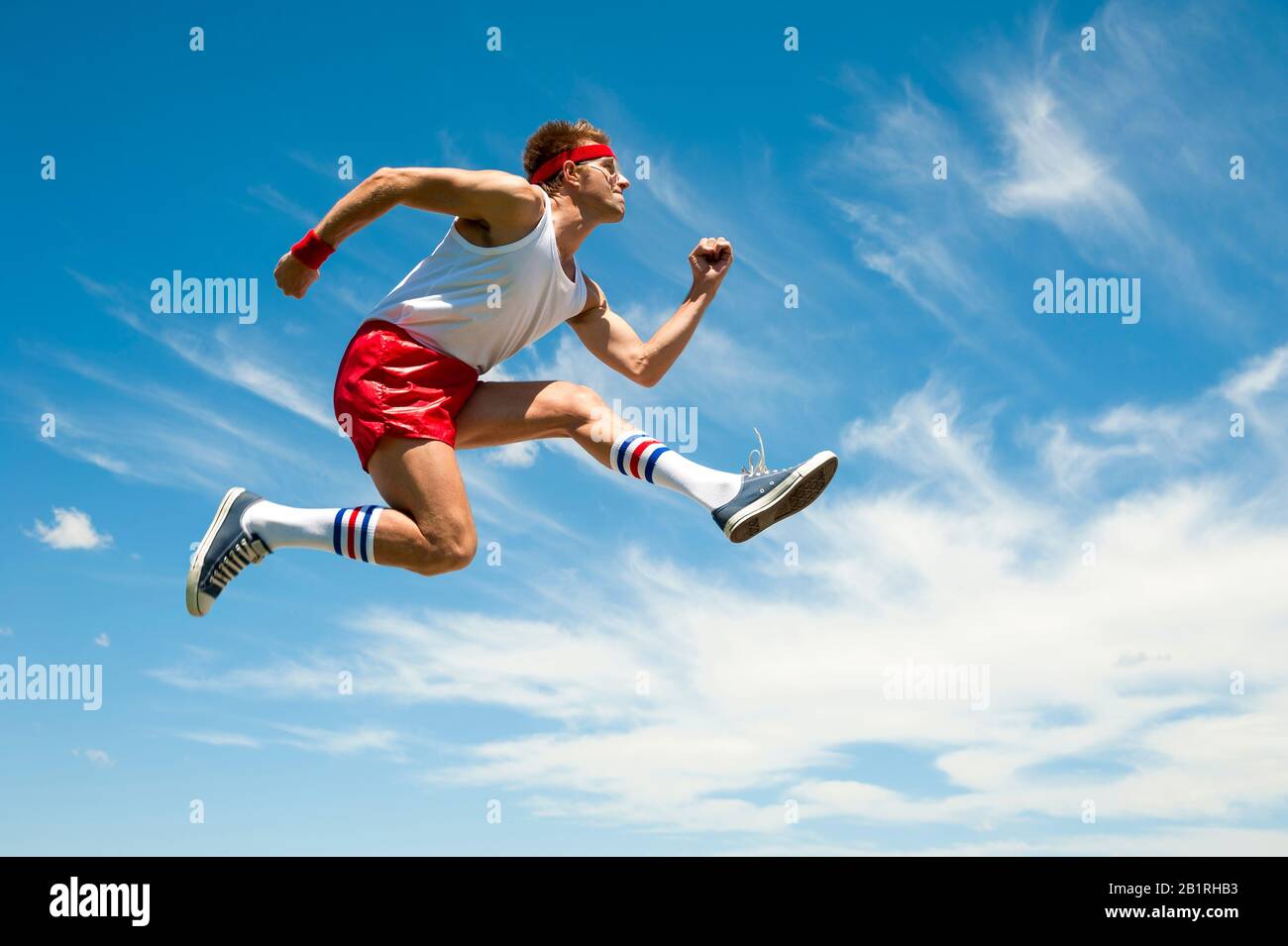 Skinny nerd athlete leaping in the long jump wearing vintage athletic wear  against a bright blue sky Stock Photo - Alamy