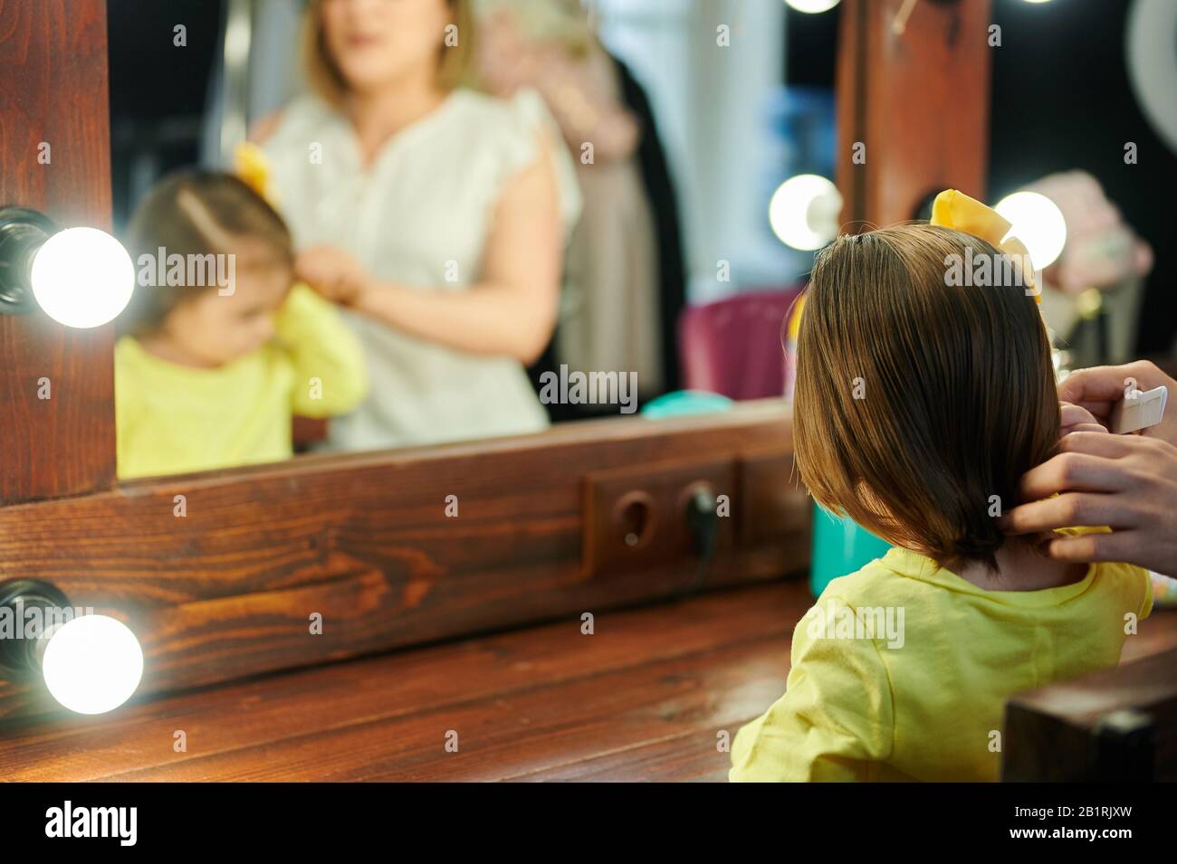 Baby girl comb her hair infront of mirror in dressing room with mom Stock Photo