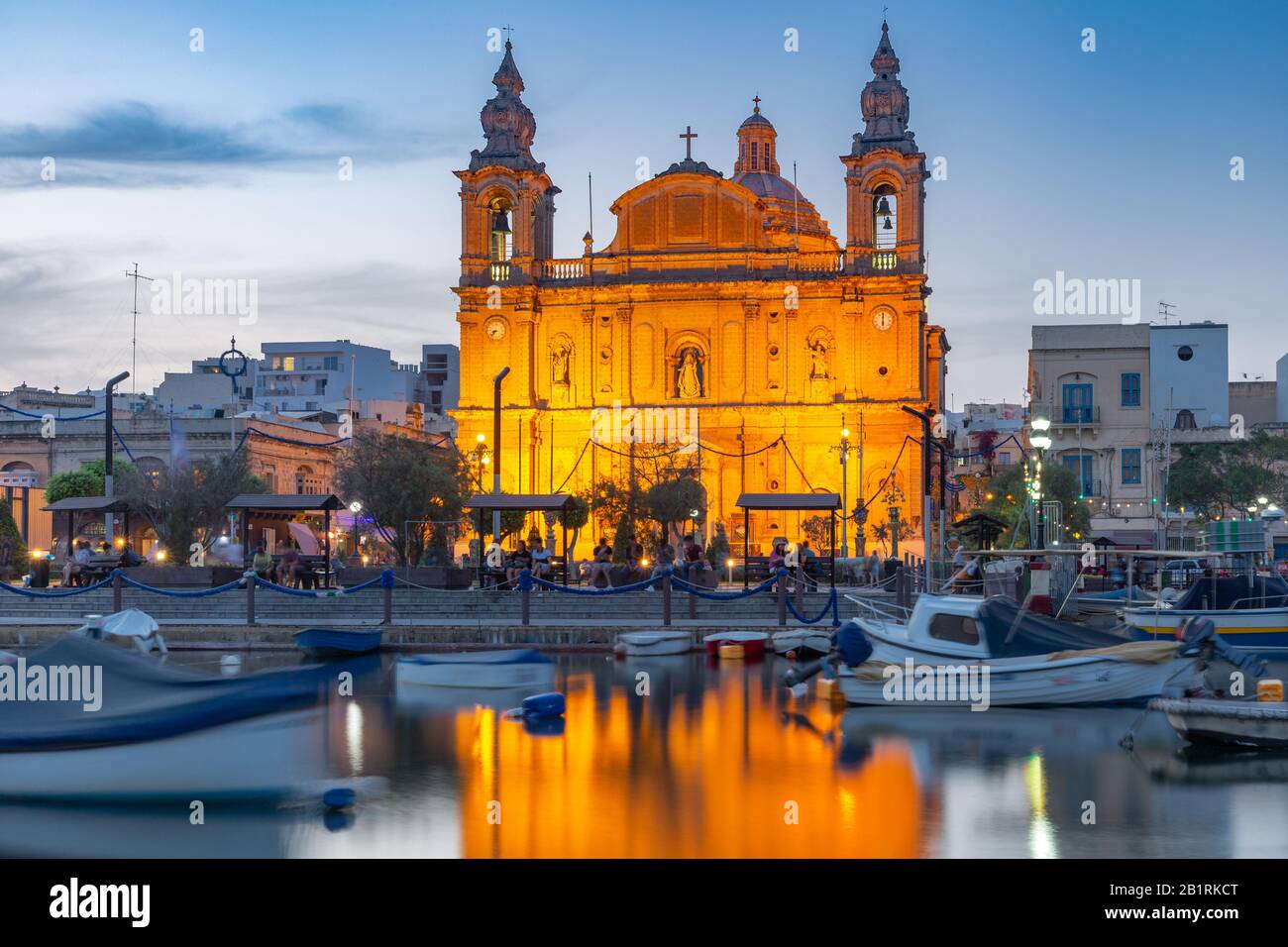 Valletta harbour with yachts and fishing boats, Msida Parish Church of Saint Joseph at sunset, Malta Stock Photo