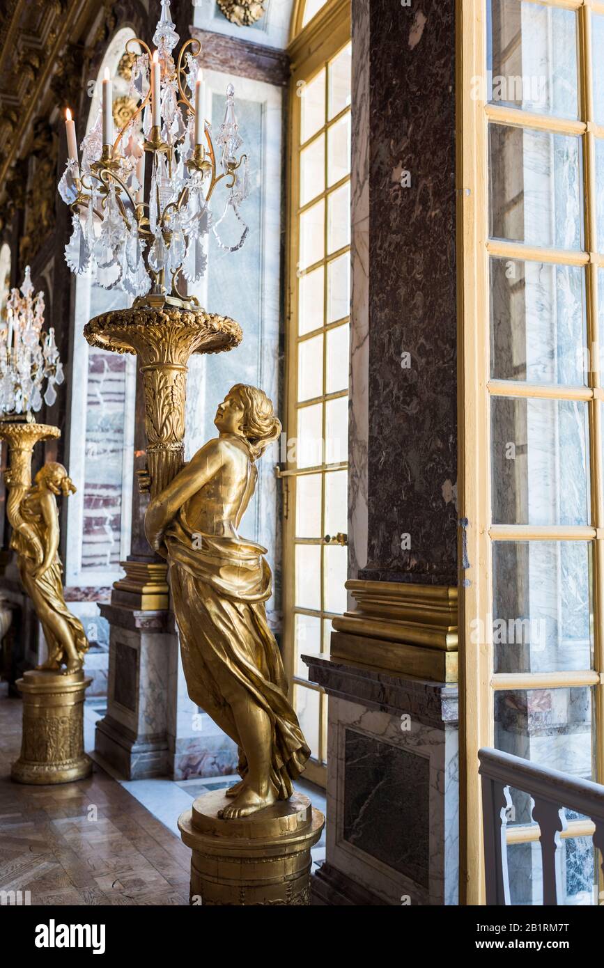Versailles, France - July 10, 2019: Gold Statues of woman holding ornate Chandeliers, The Hall of Mirrors, Palace of Versailles, France. Stock Photo
