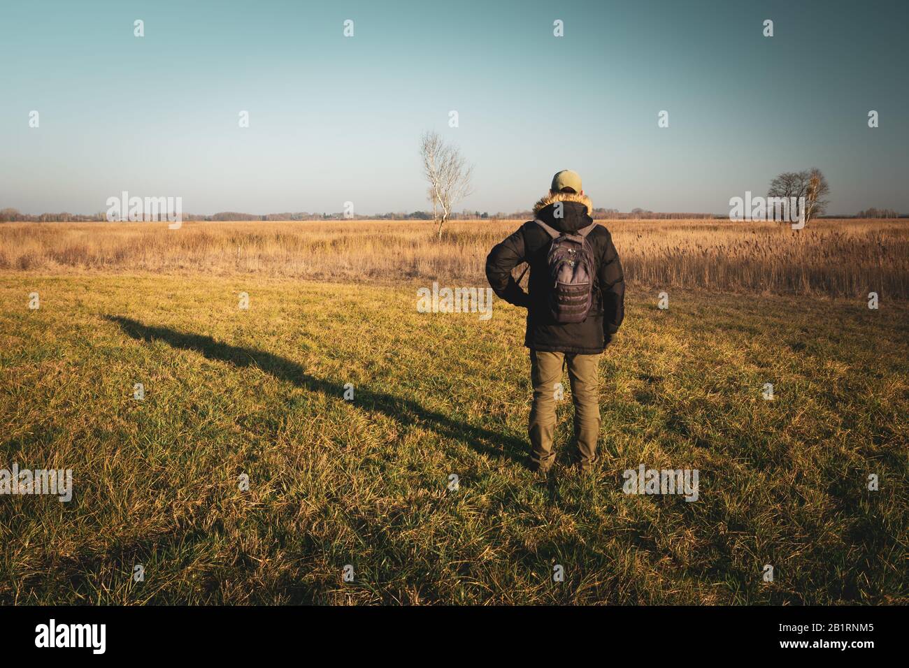 Male traveler with a backpack standing on the meadow Stock Photo